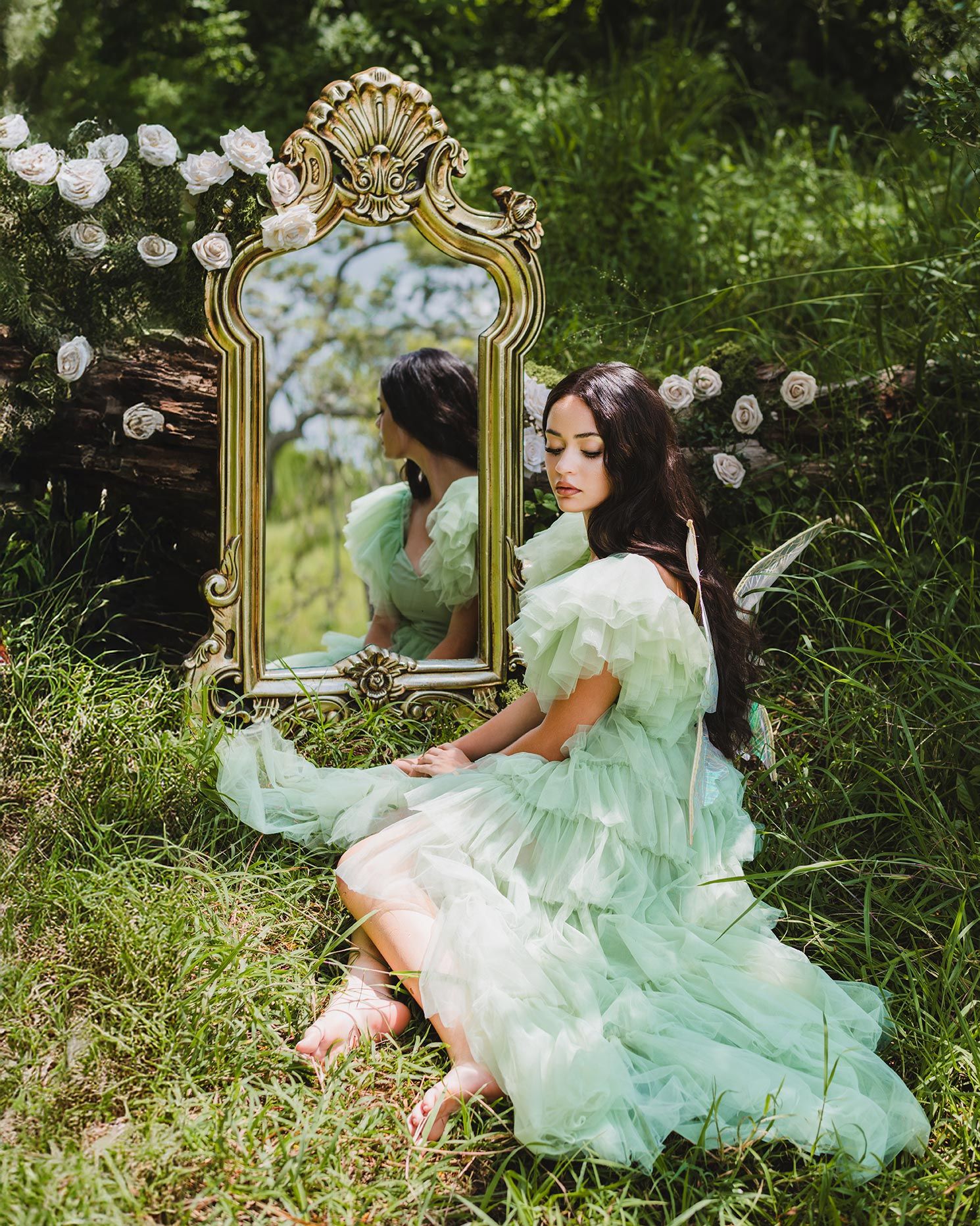 Ethereal mint green tulle dress flows around a vintage ornate mirror in a garden setting with white roses.
