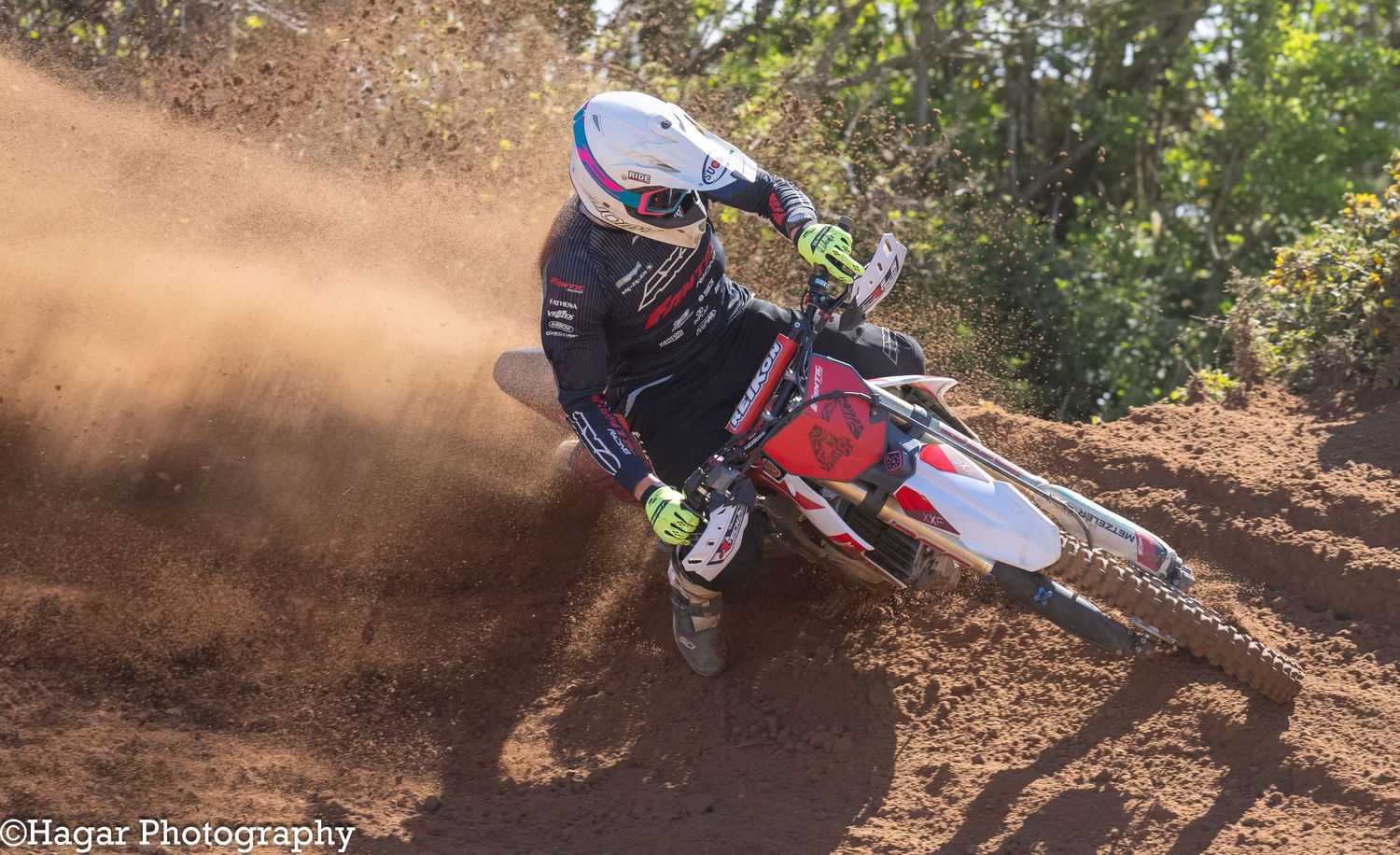 A white motocross bike number 47 drives out of a berm
