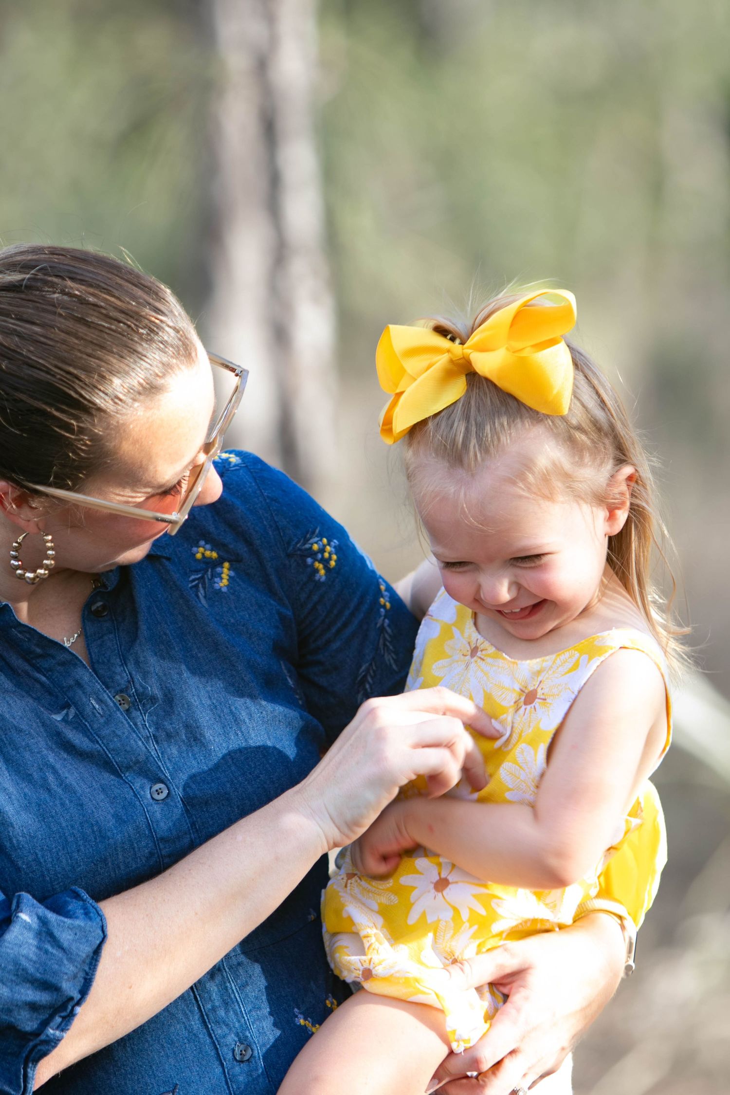 Mother and daughter in matching yellow and blue sharing joyful moment outdoors.