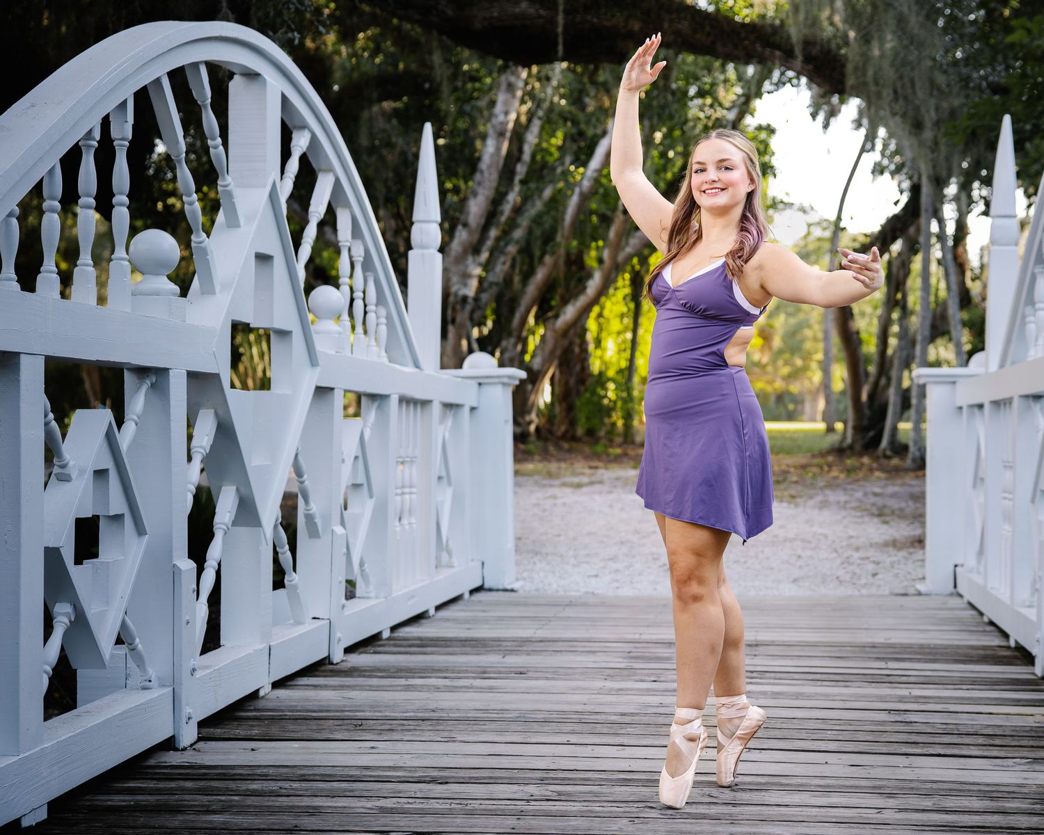 Woman in purple dress poses playfully in sequence of shots on white wooden bridge walkway.