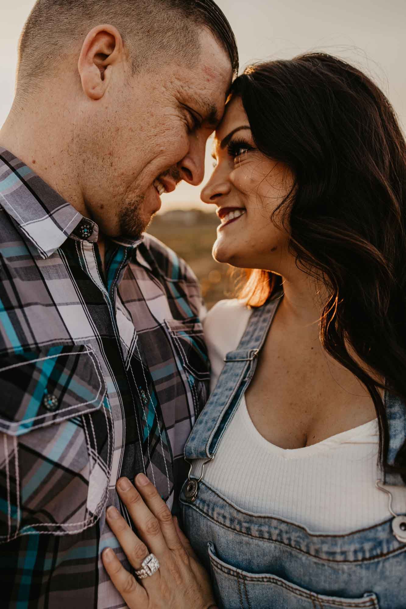 Close-up portrait of a couple touching foreheads and smiling while wearing plaid and denim.
