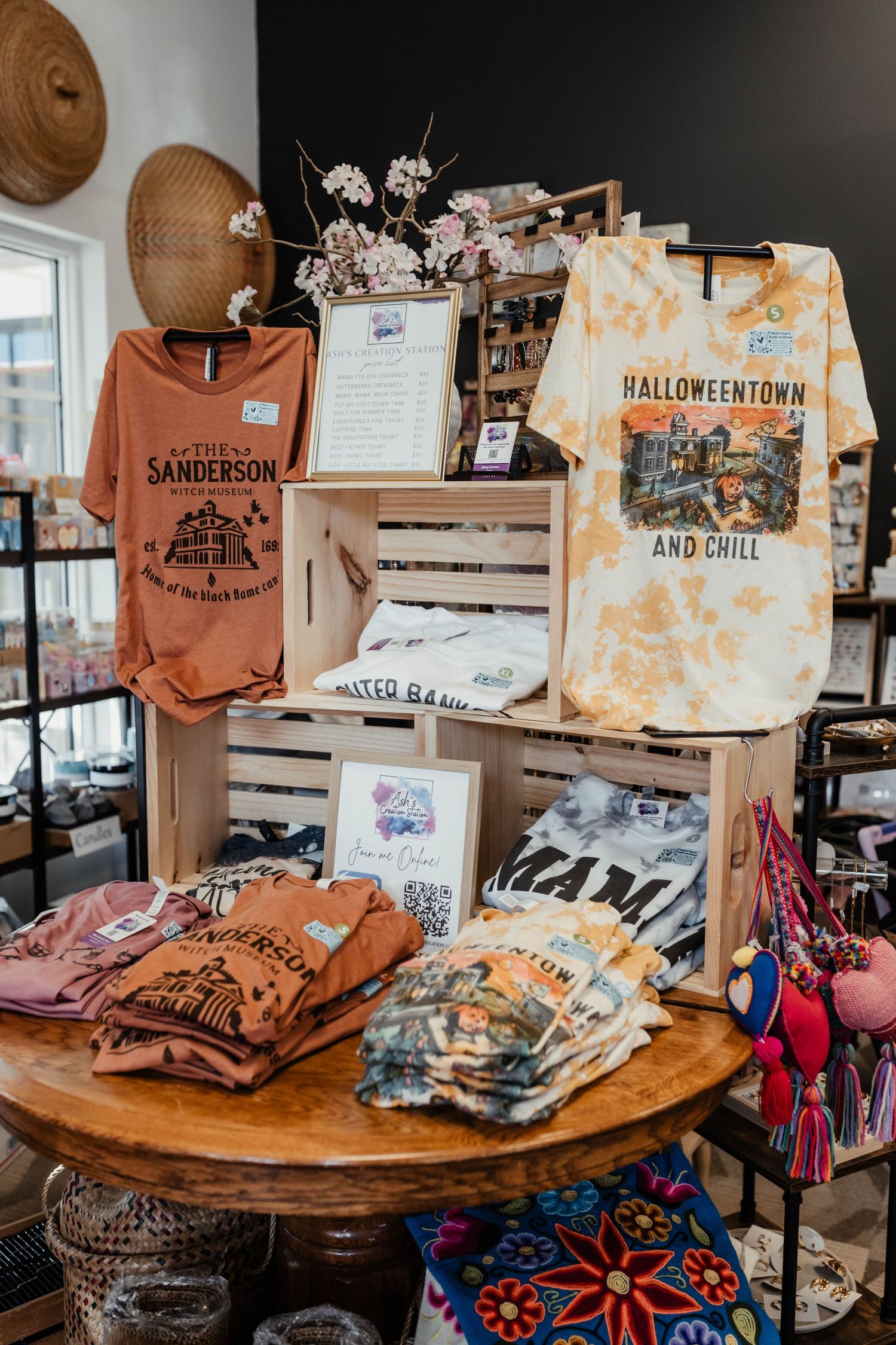Halloween and autumn themed t-shirts displayed on wooden crates in a retail store setting.