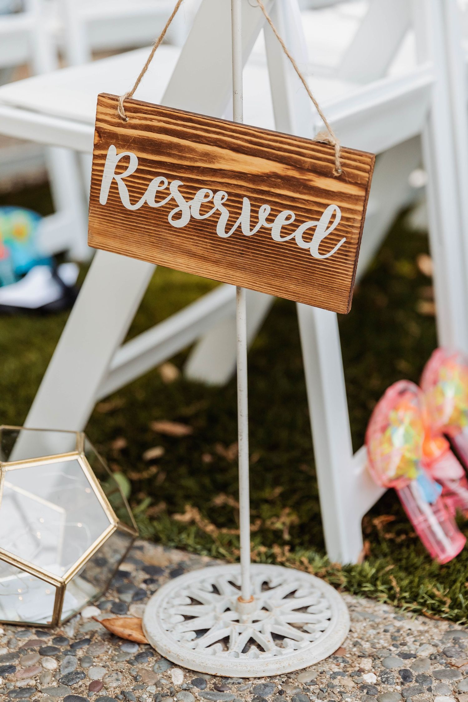 Rustic wooden wedding signs with white lettering displayed on white folding chairs.