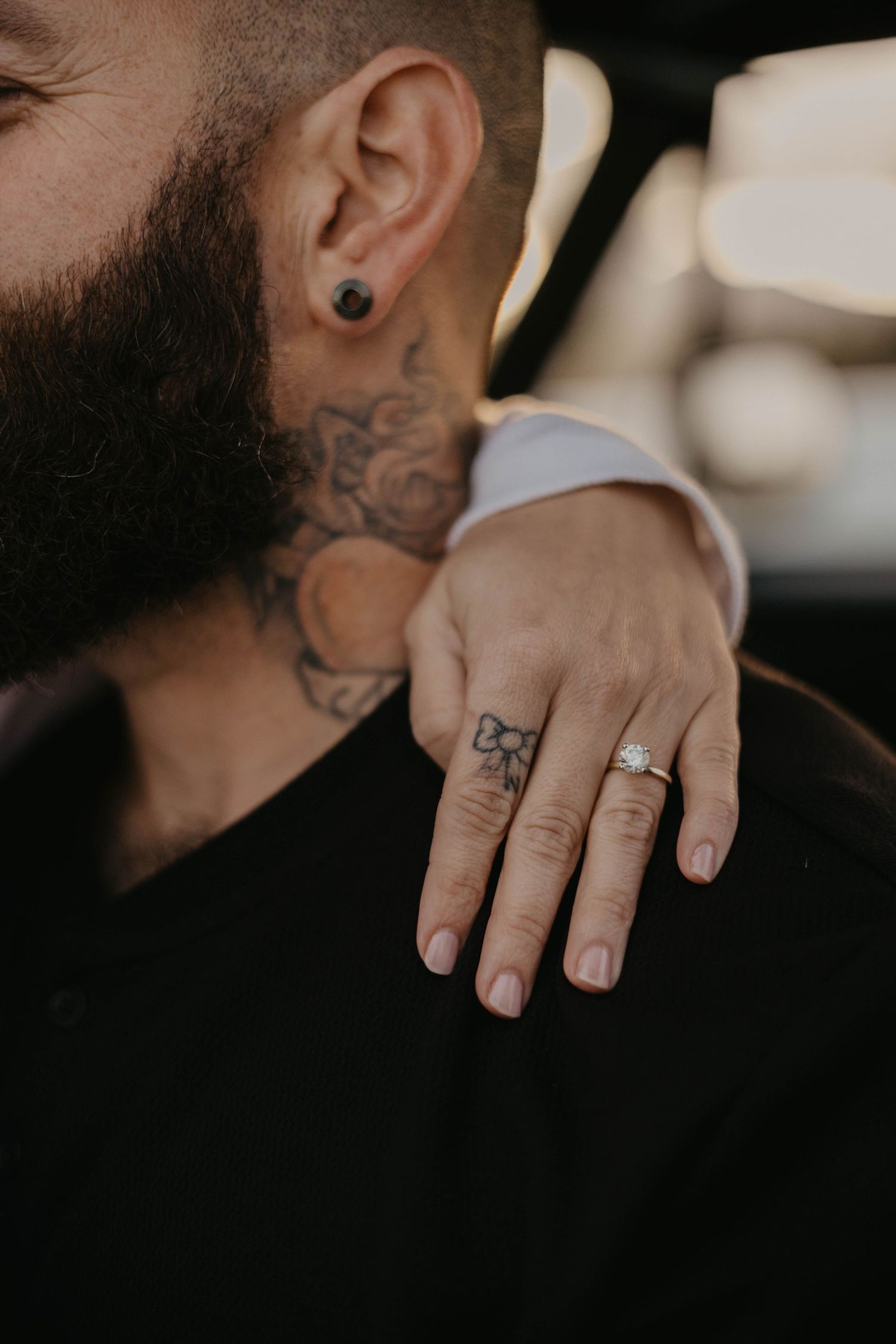 Close-up of hands with tattoos and rings showing intimate connection.