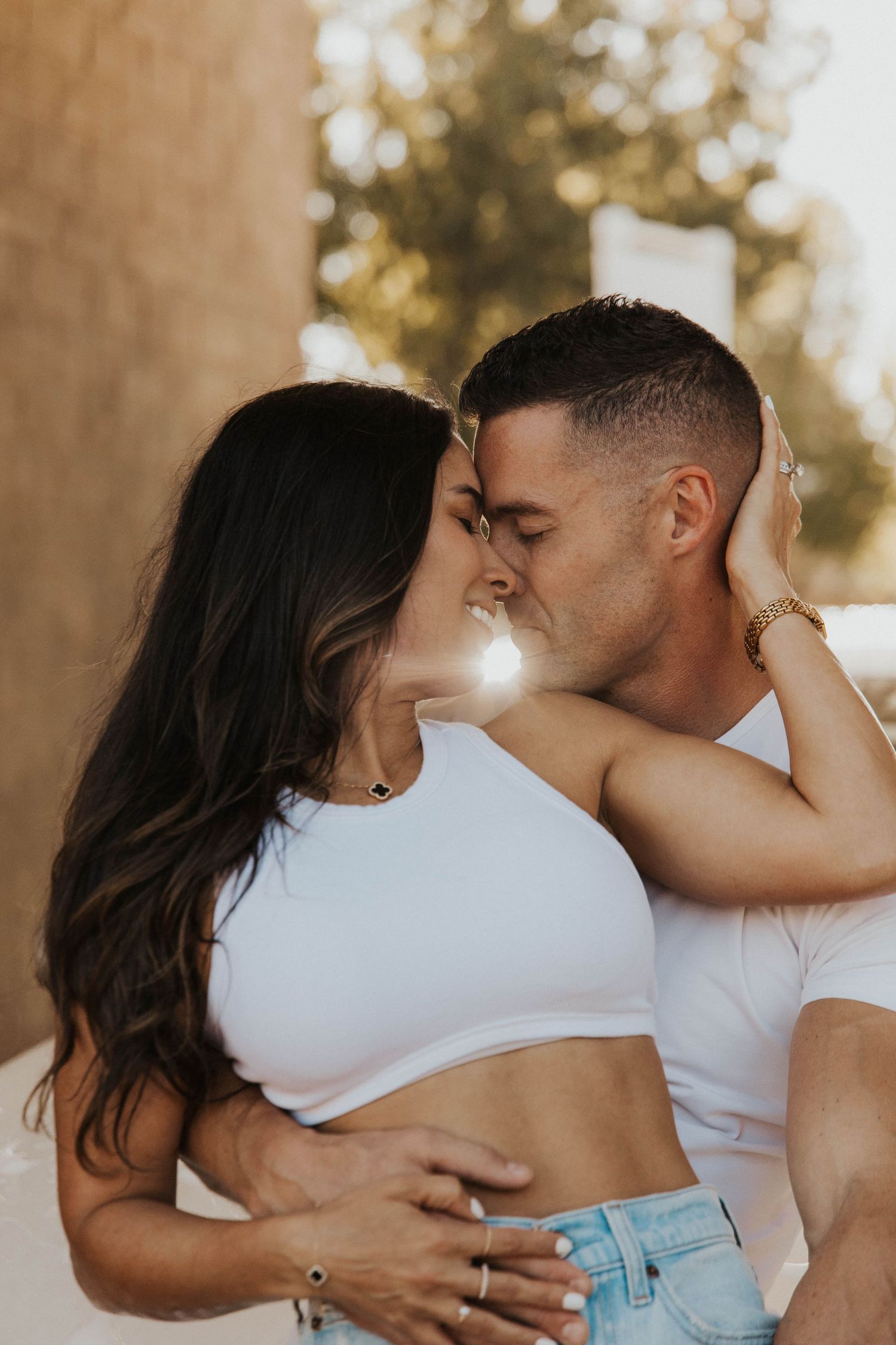 Romantic couple in white and denim embracing in warm sunlight.