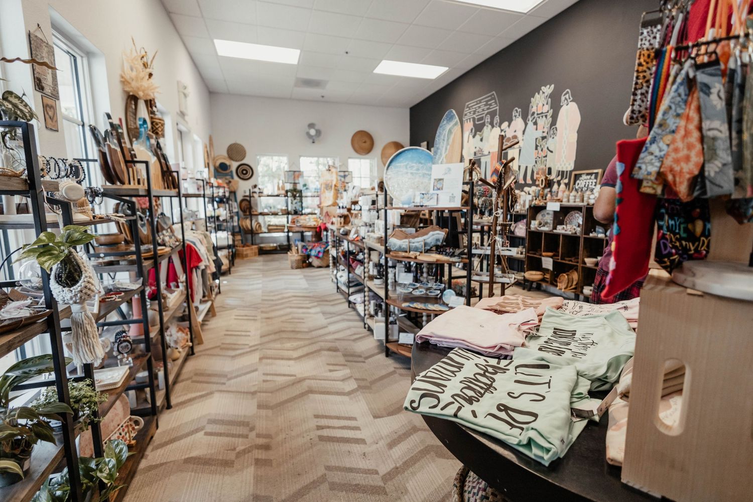 Boutique shop interior with herringbone floors and shelving units filled with various retail merchandise.