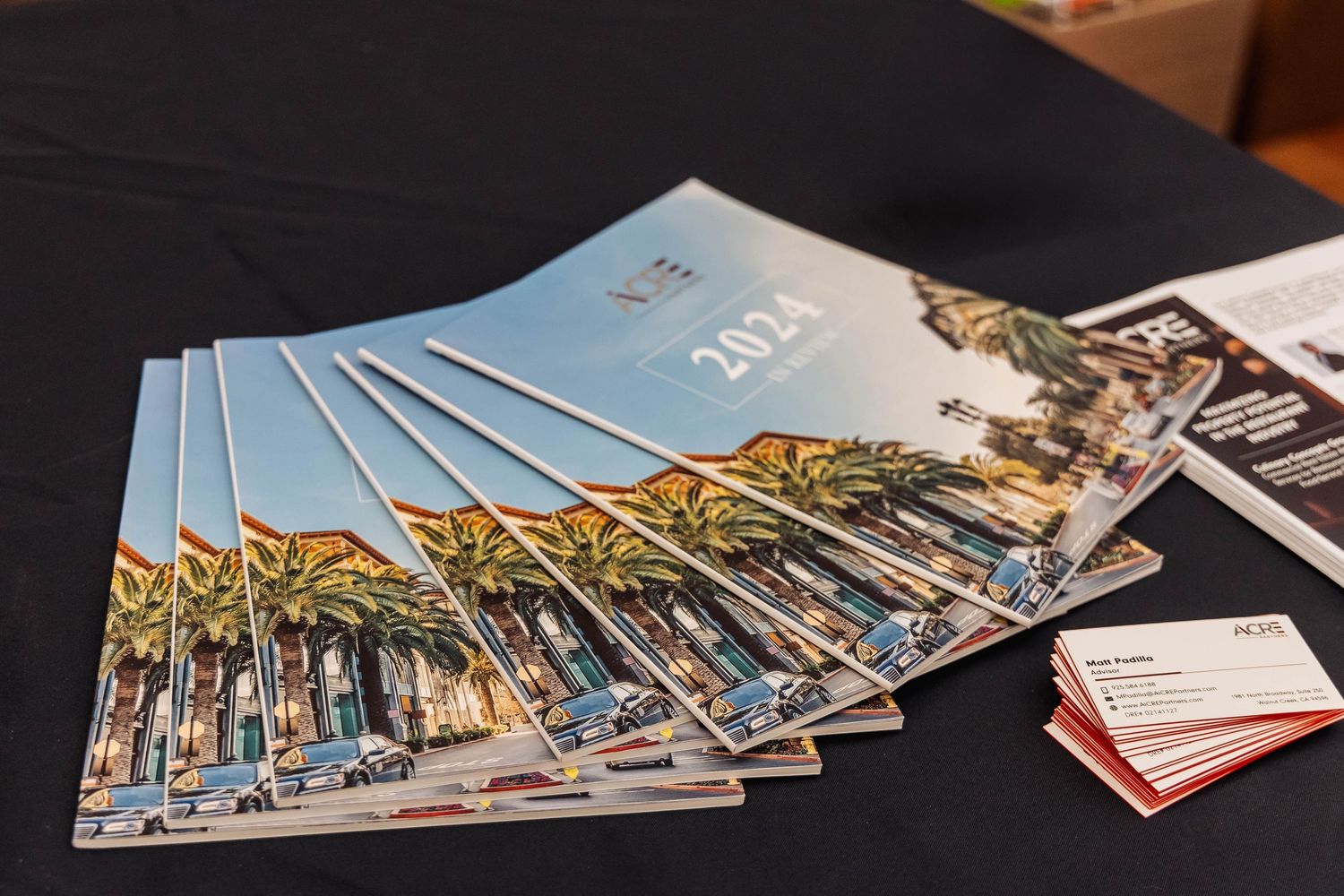 Stack of event programs or brochures fanned out on dark table surface.