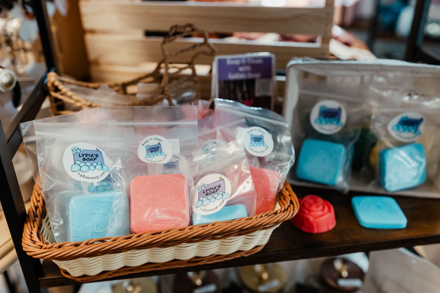 Colorful soaps displayed in wicker basket with branded packaging.