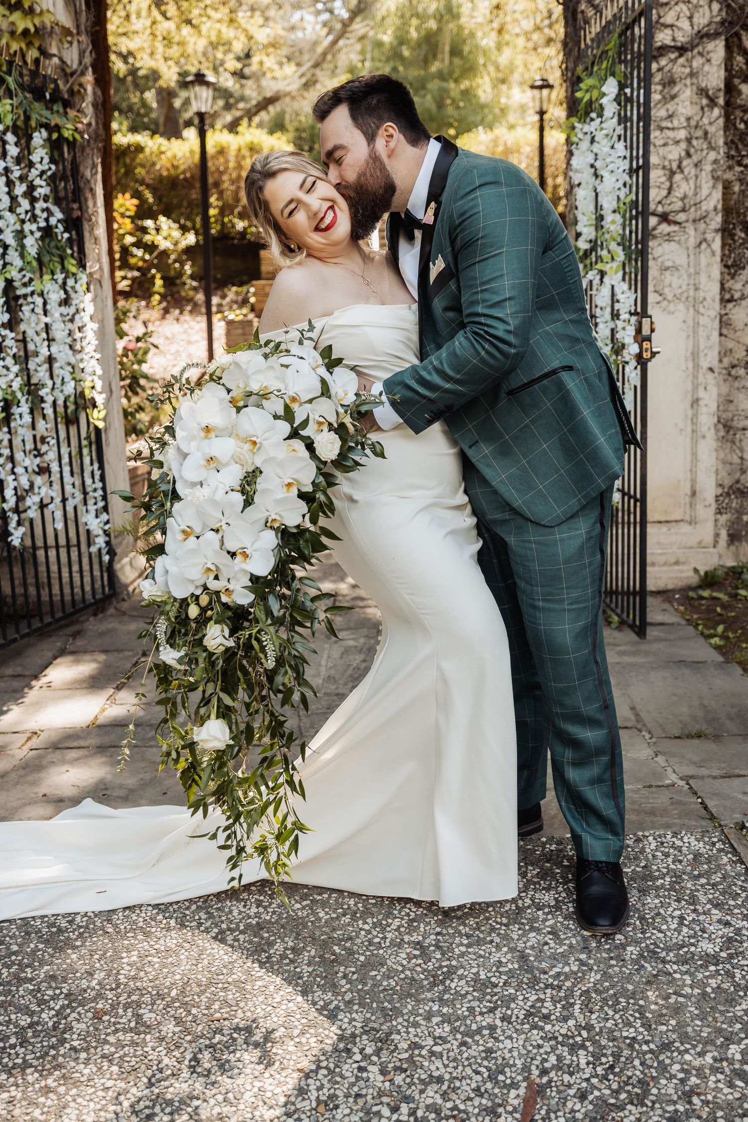 Romantic wedding portraits against an ornate iron gate in golden afternoon light.