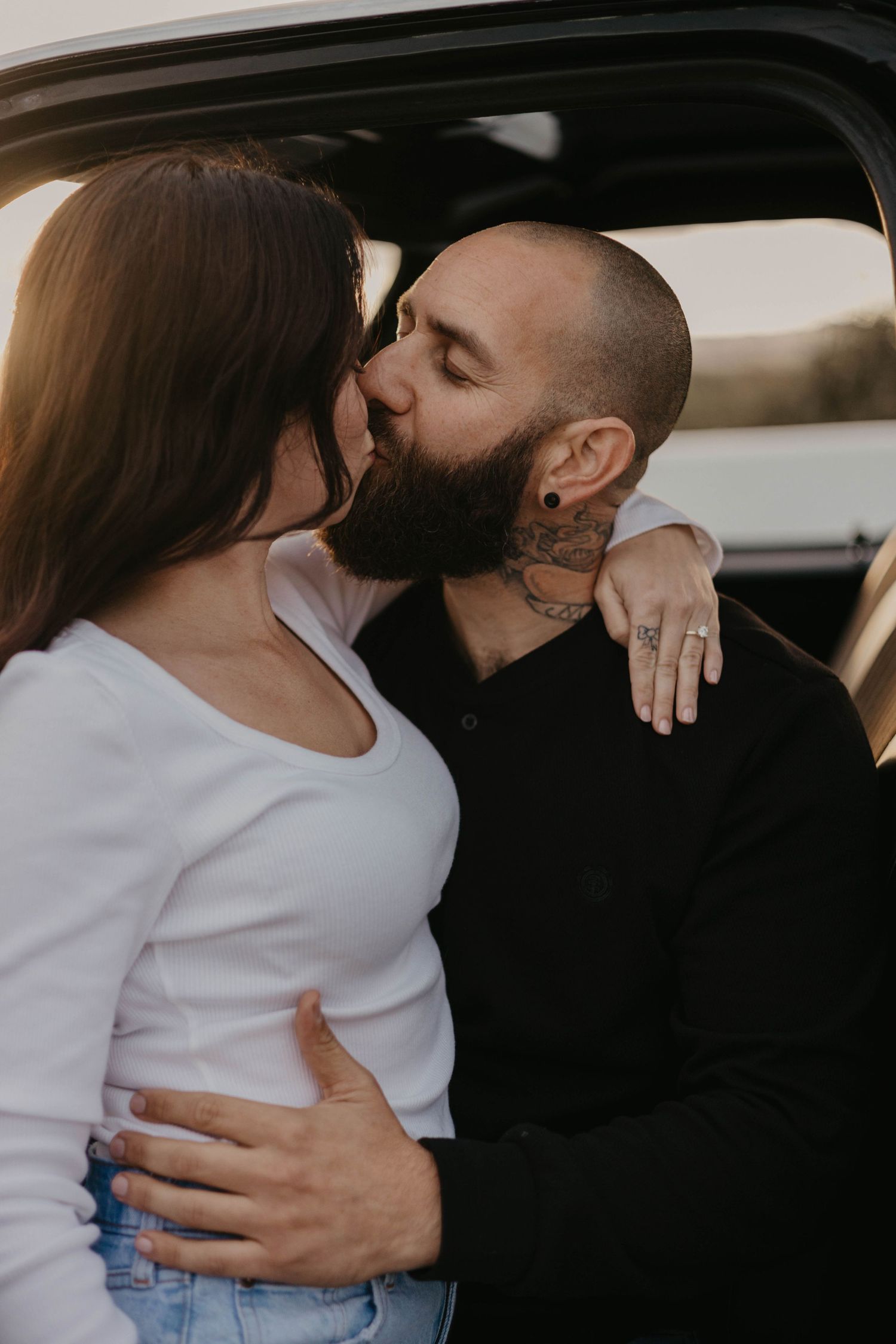 Intimate couple's moment captured in black and white tones inside car.
