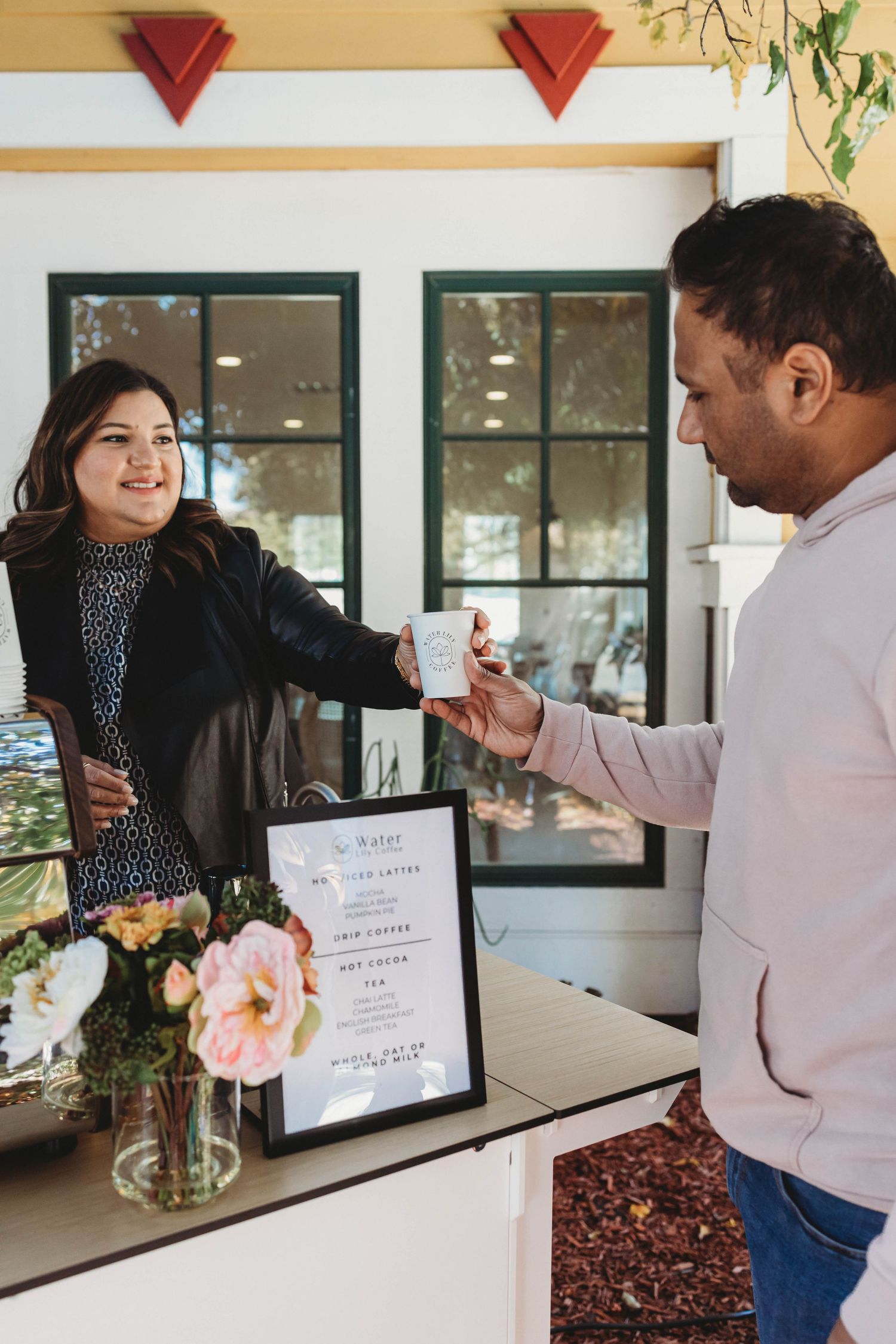 Coffee shop counter with menu displays and fresh flowers in vases.