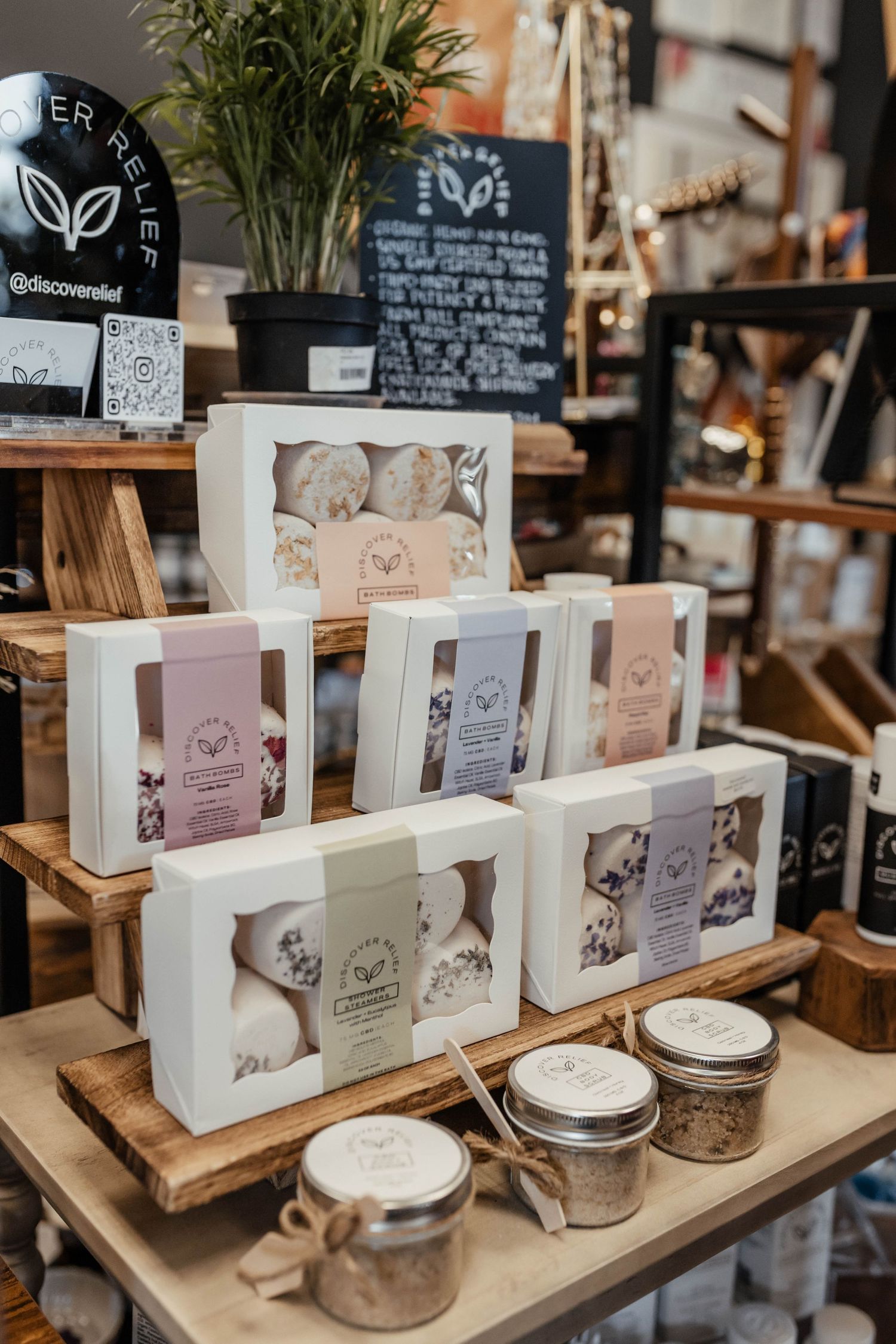 Rustic retail display of packaged bath and beauty products on wooden tiered stands.