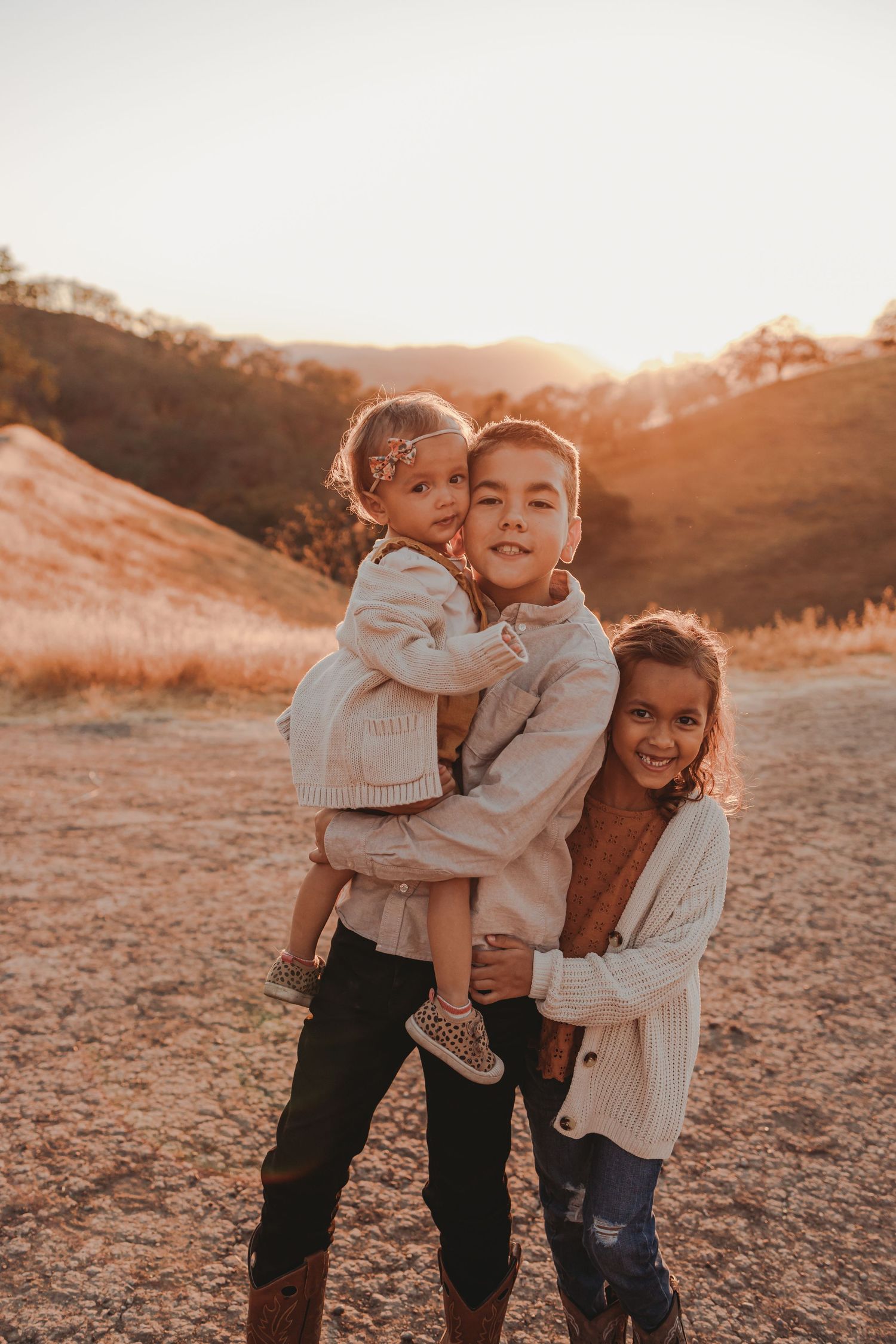Children playing and hugging together outdoors during golden hour.