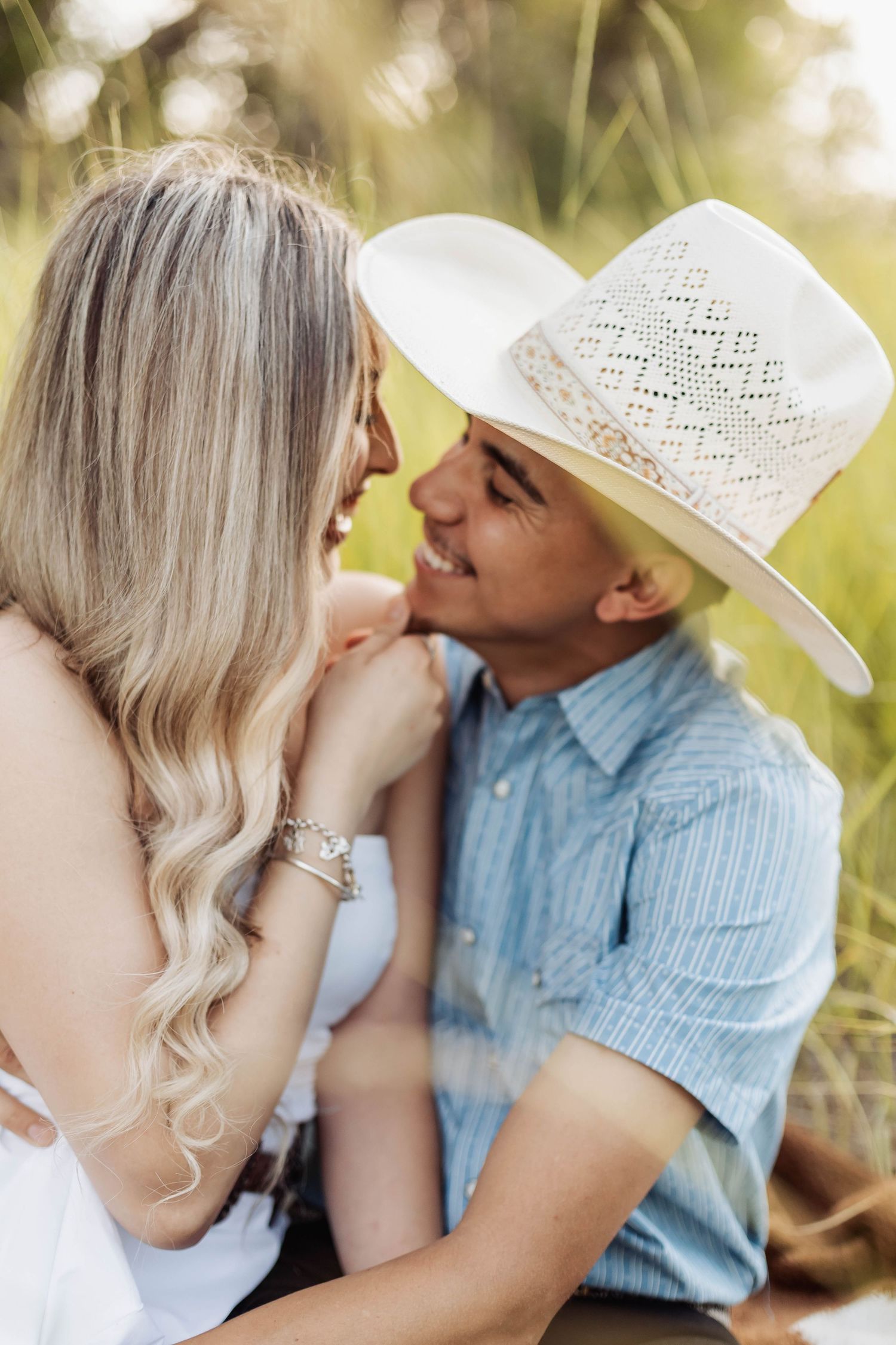 Intimate close-up of couple sharing tender moment in sunlit grass field.