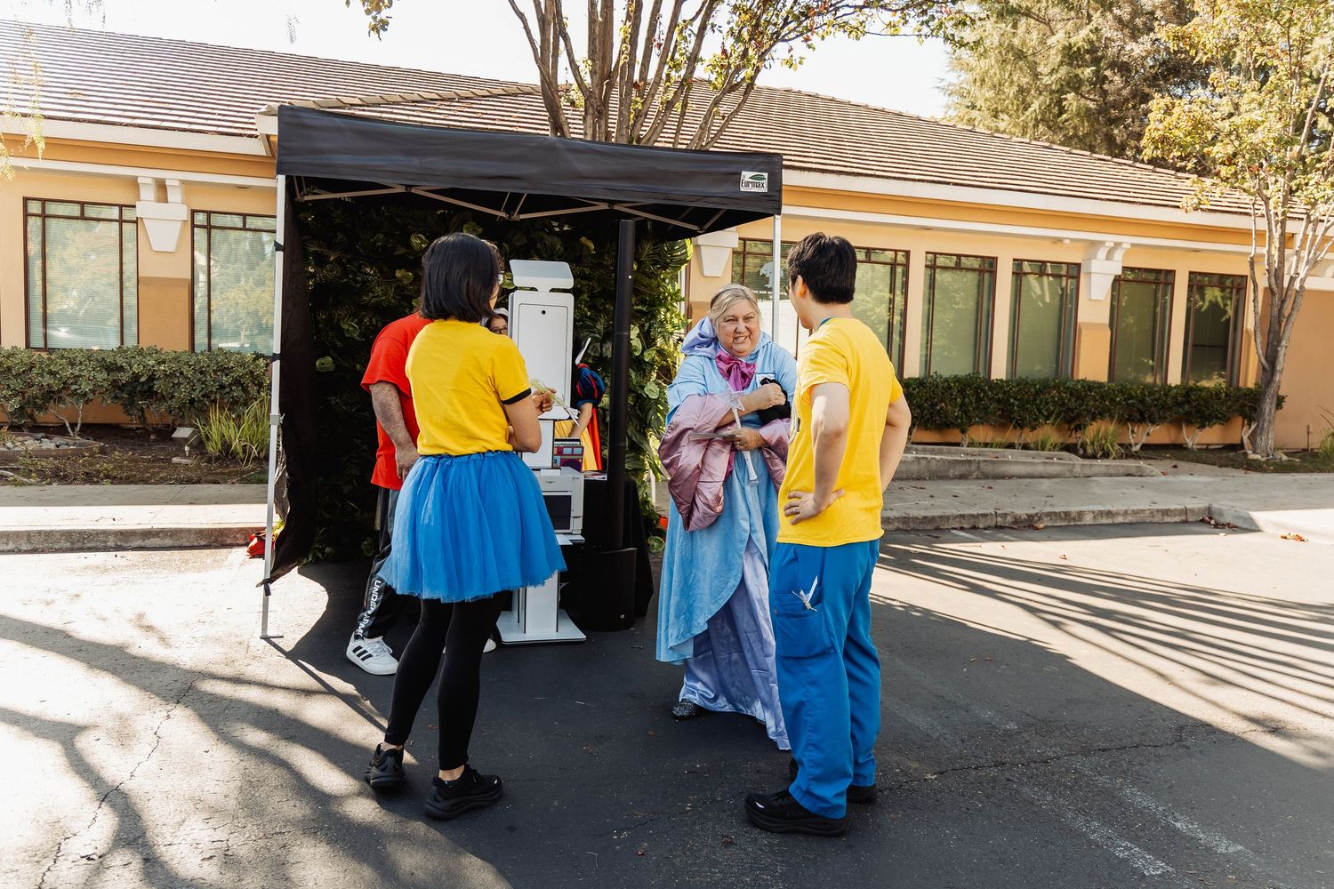 People in colorful costumes walking along a pathway during an outdoor gathering.