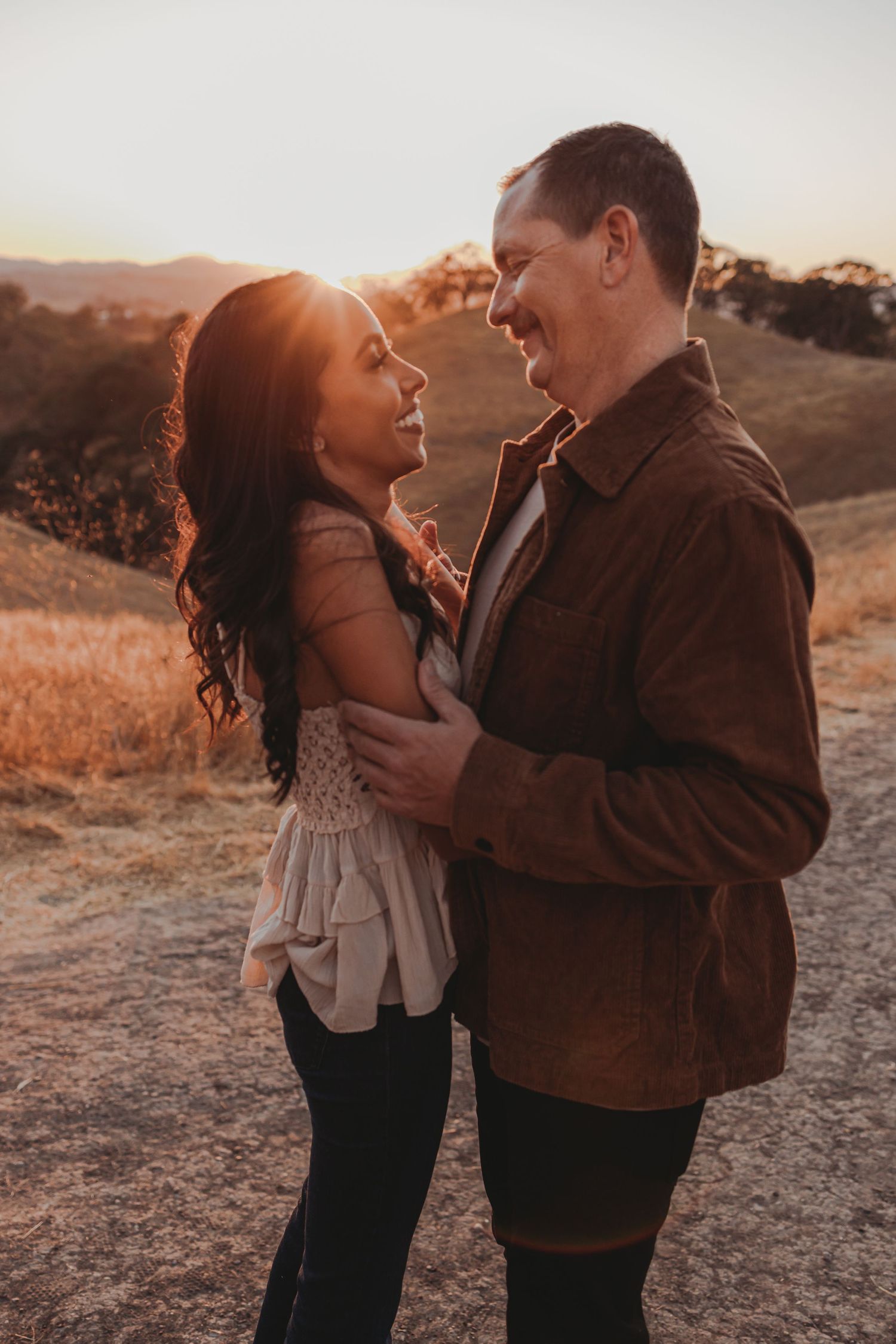 Romantic couple embracing on hiking trail during sunset.