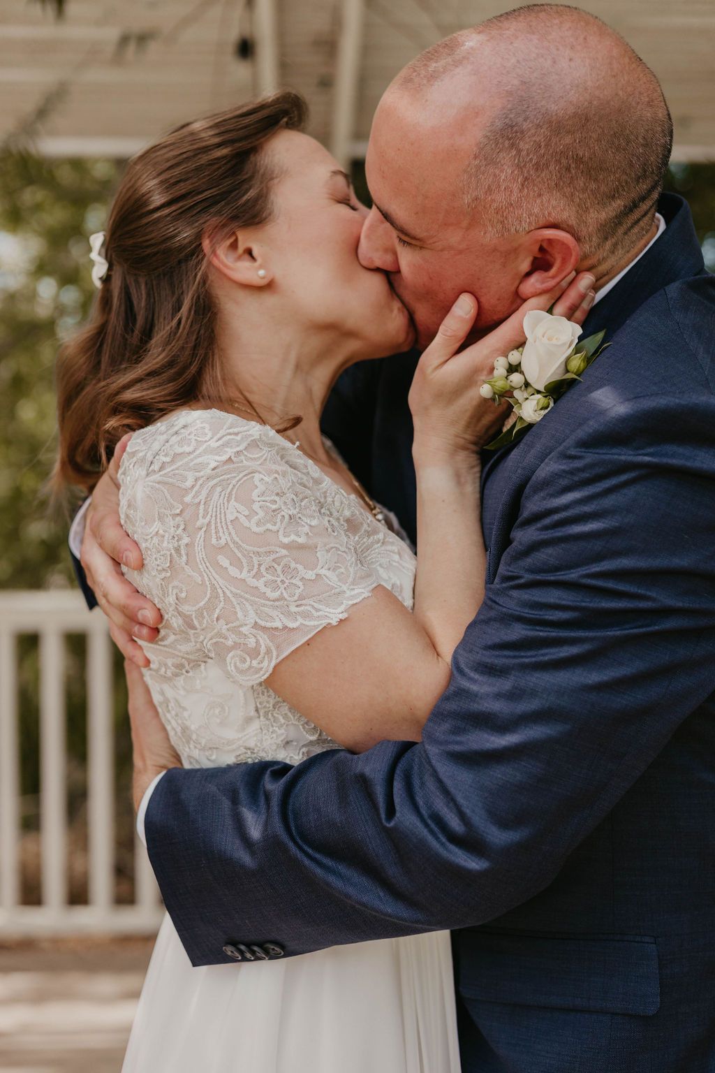 Romantic first kiss between newlyweds during outdoor wedding ceremony.