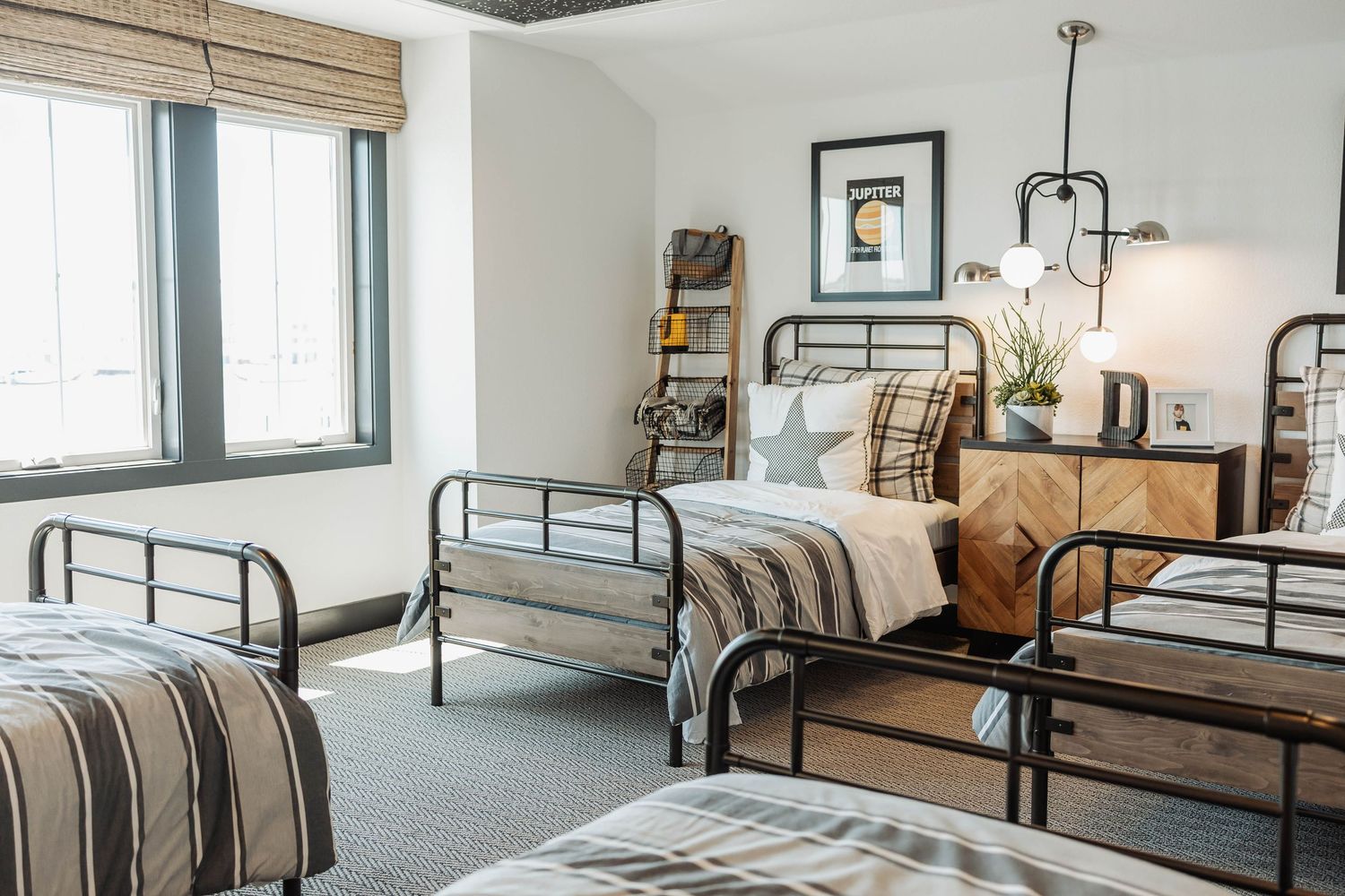 Modern dormitory room interior with multiple beds, white walls, and natural lighting.