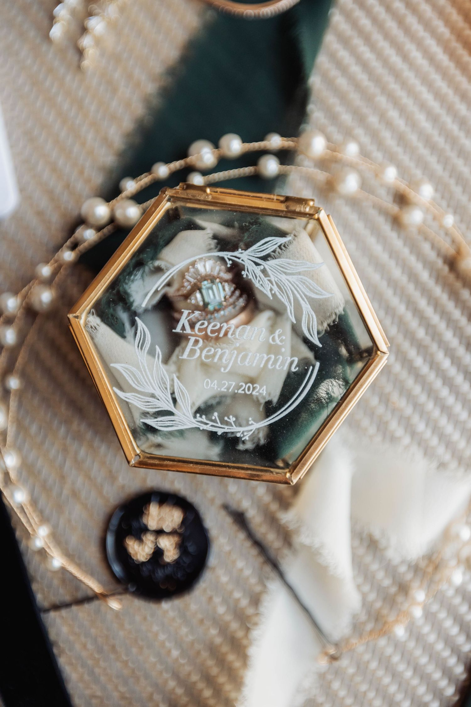 Elegant gold hexagonal wedding place cards with engraved names displayed on textured fabric.