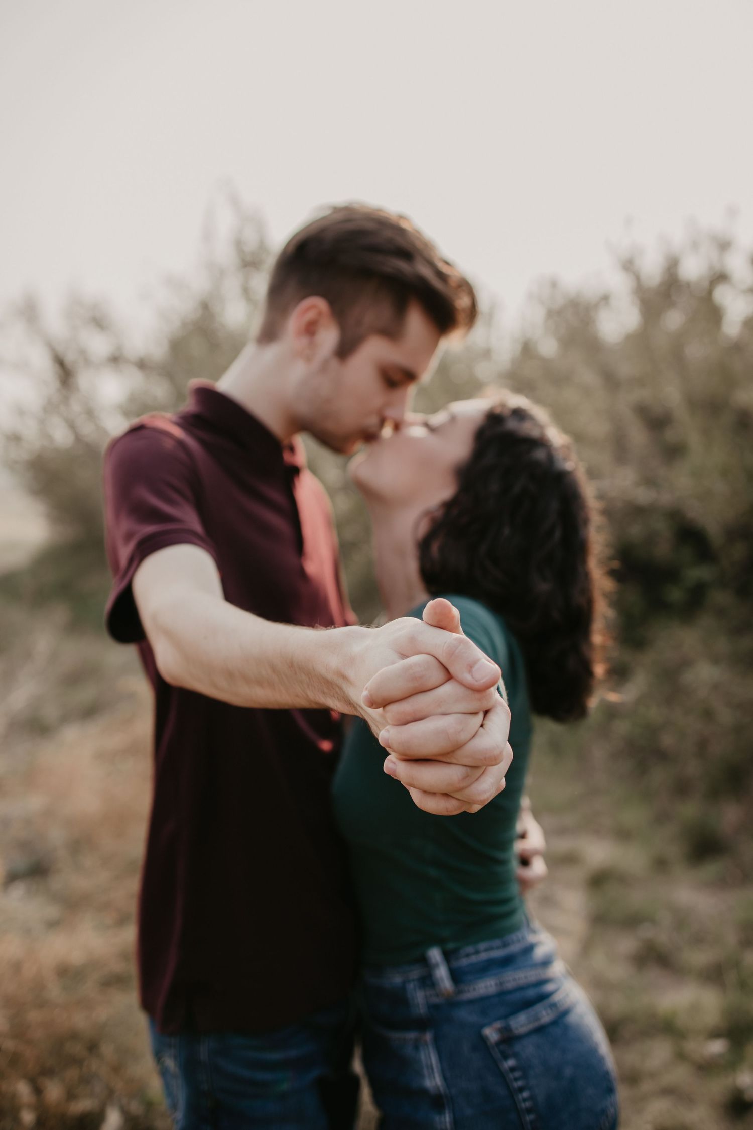 A romantic couple's photoshoot showing tender moments and a ring in natural lighting.