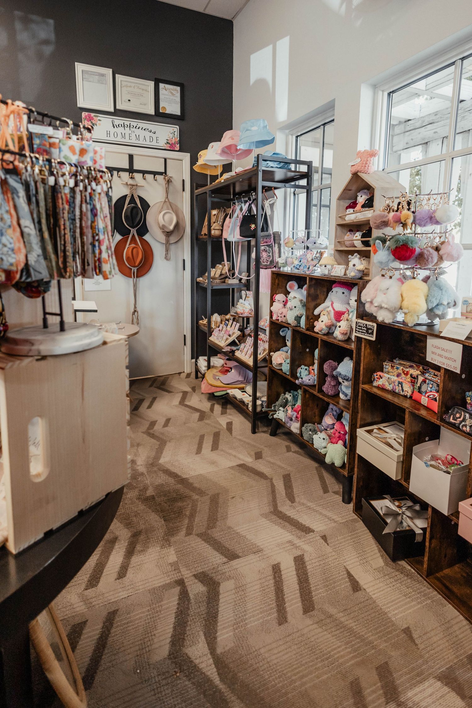 Narrow retail aisle with black accent wall, hanging instruments, and shelved merchandise on geometric flooring.