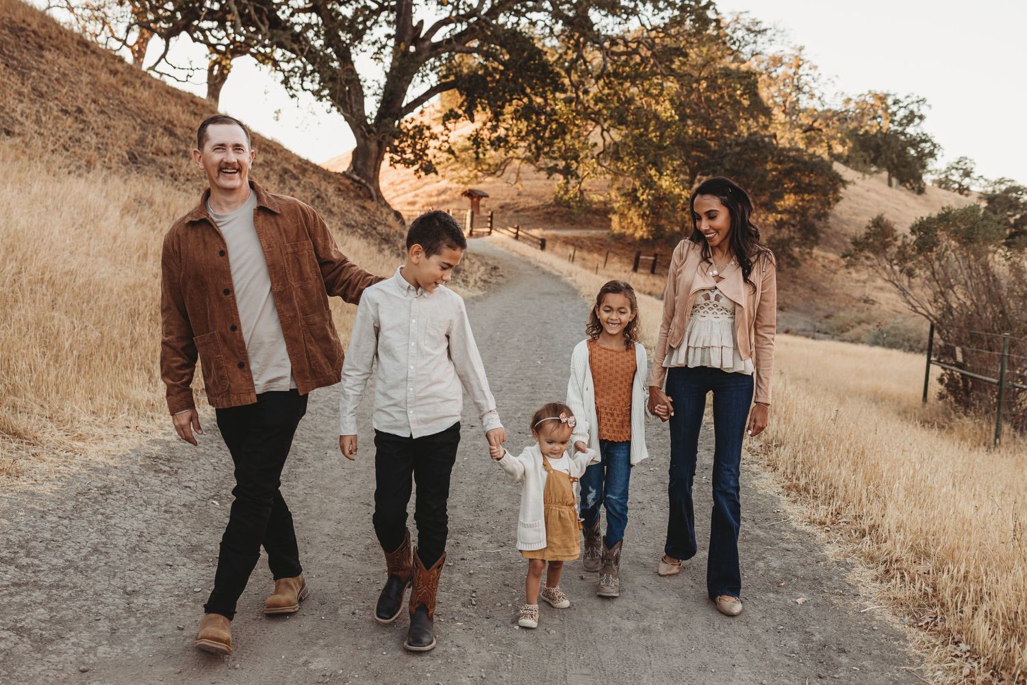 Family walking together on remote trail through golden hills.
