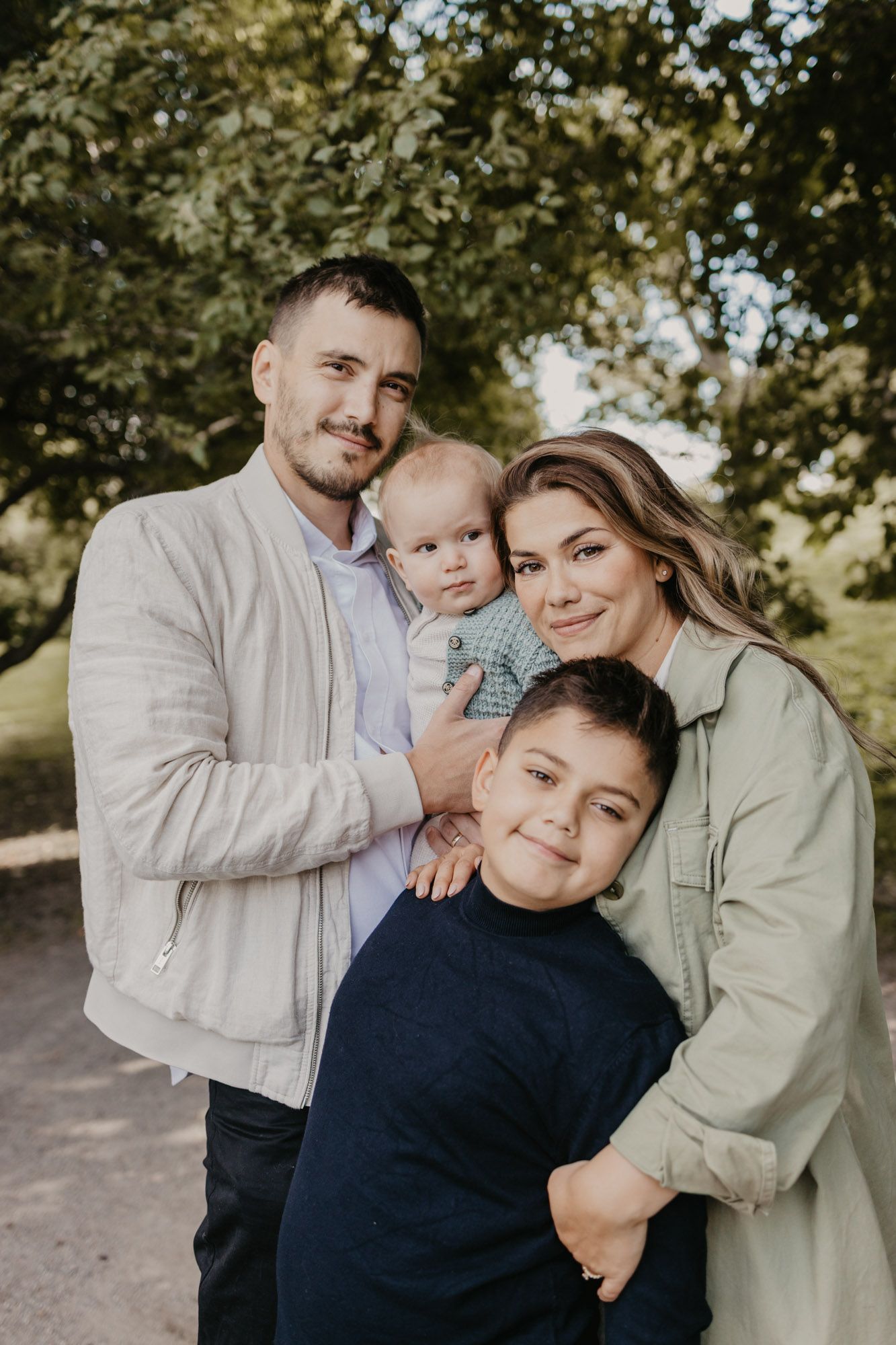 Natural light family portrait showing happy group embracing on outdoor path.