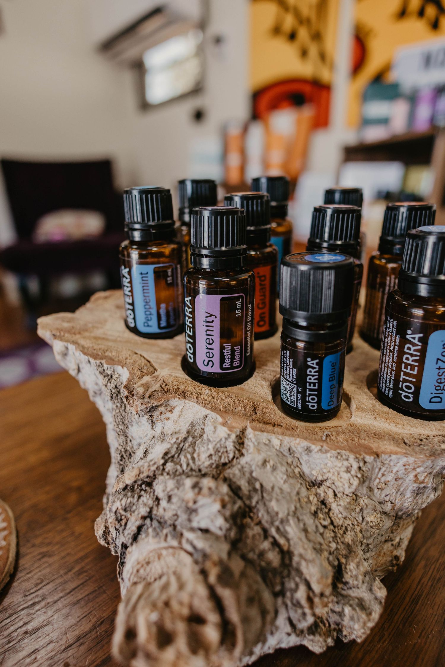 Essential oil bottles displayed on a rustic driftwood holder on a wooden surface.