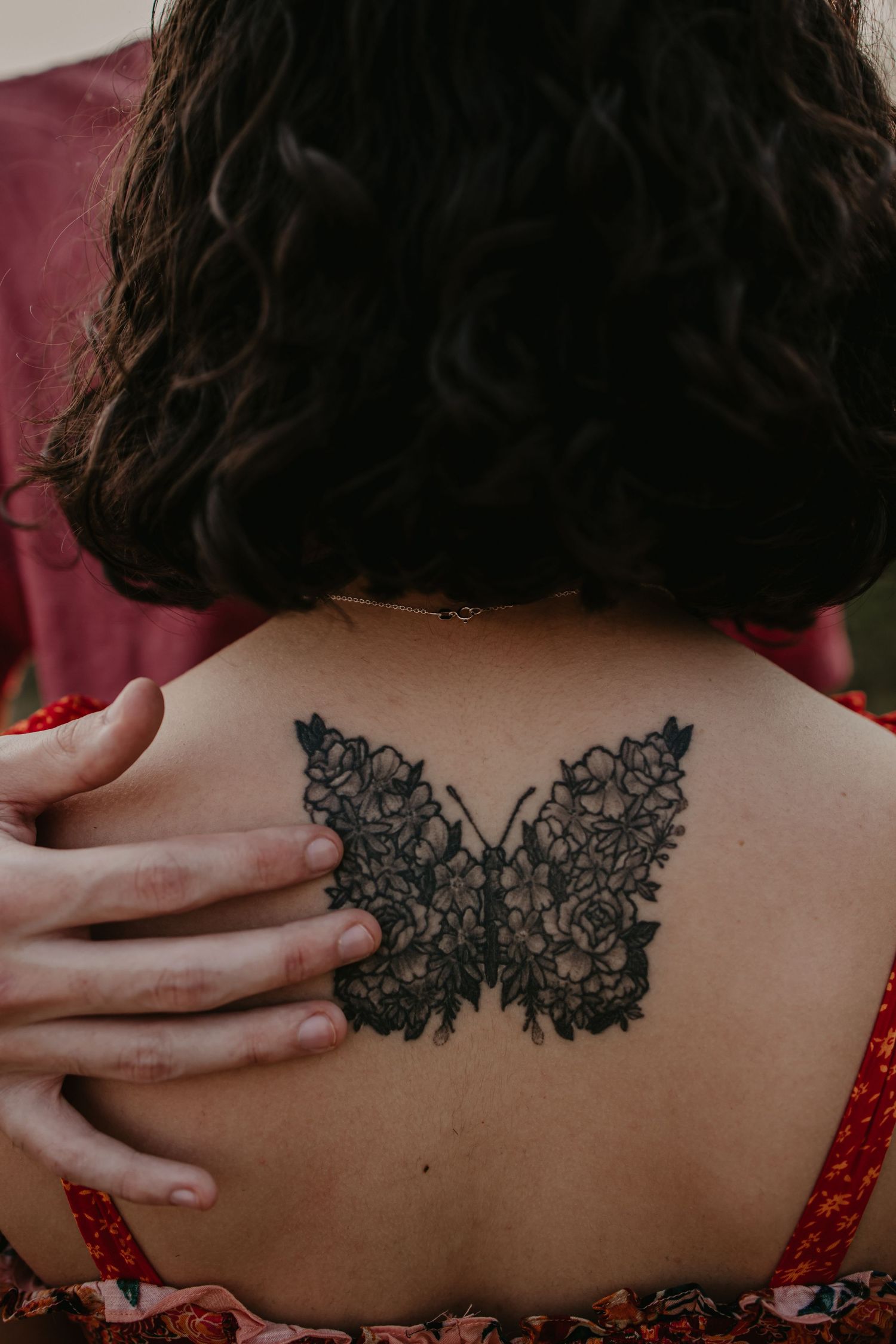 Close-up of an intricate lace-like tattoo design across someone's upper back.