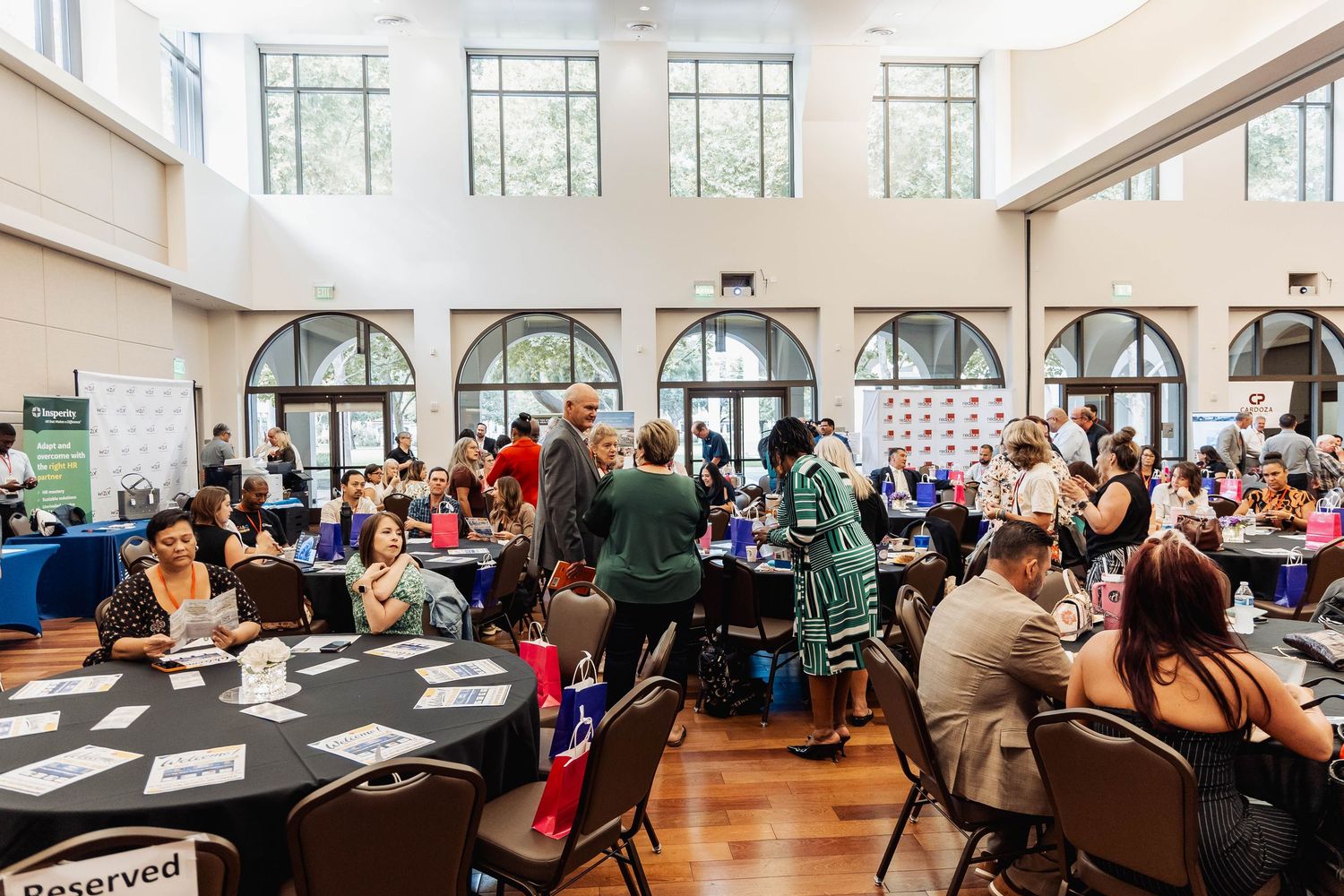 Large conference room filled with attendees seated at round tables for an event.