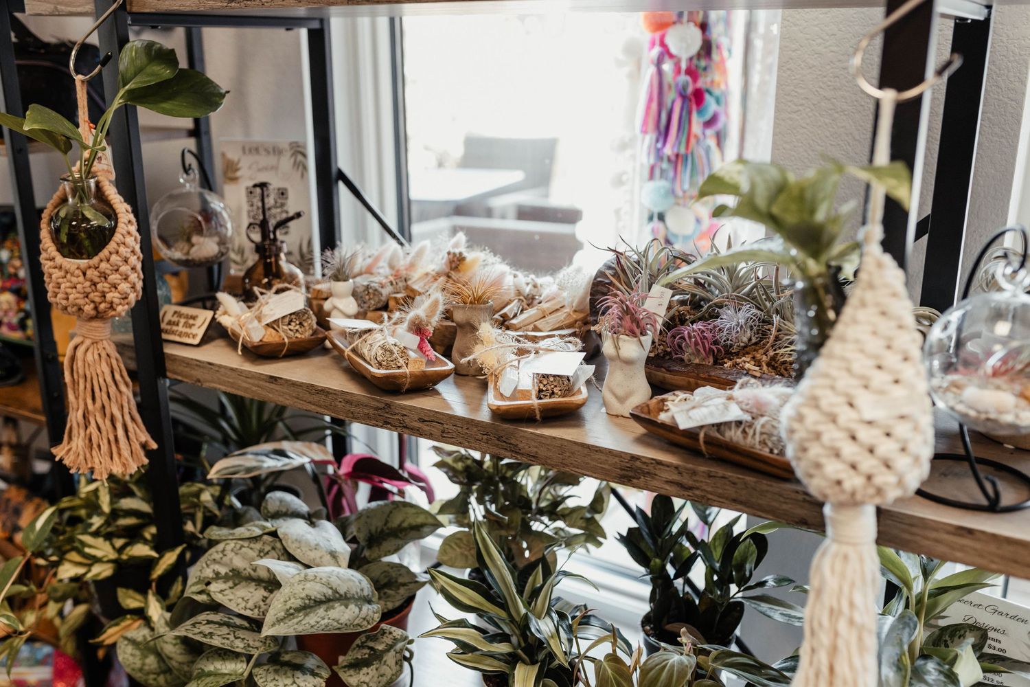 Retail display shelf with decorative macrame, plants and handcrafted items.