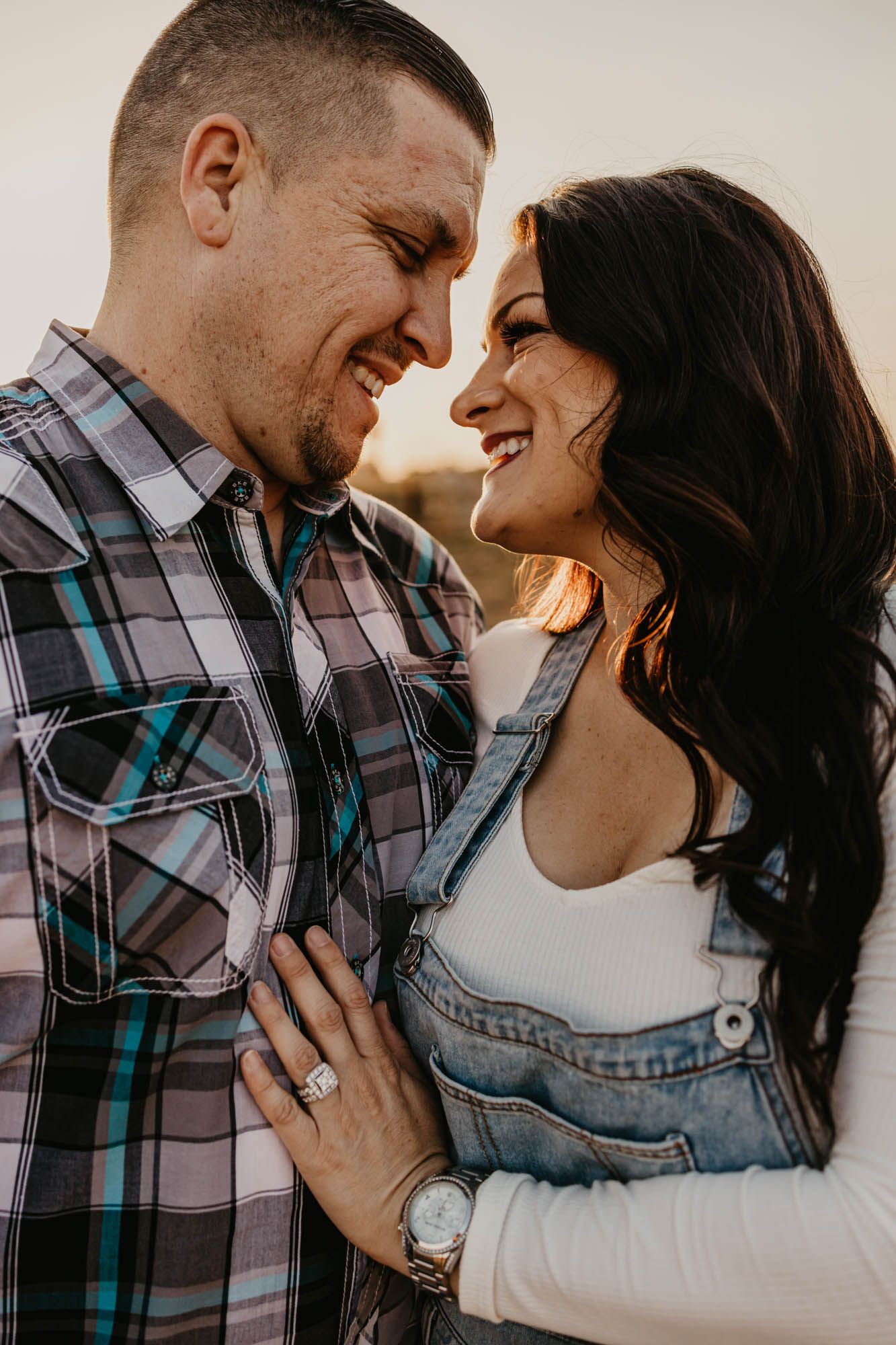 A joyful couple shares a loving moment during their engagement session at golden hour.