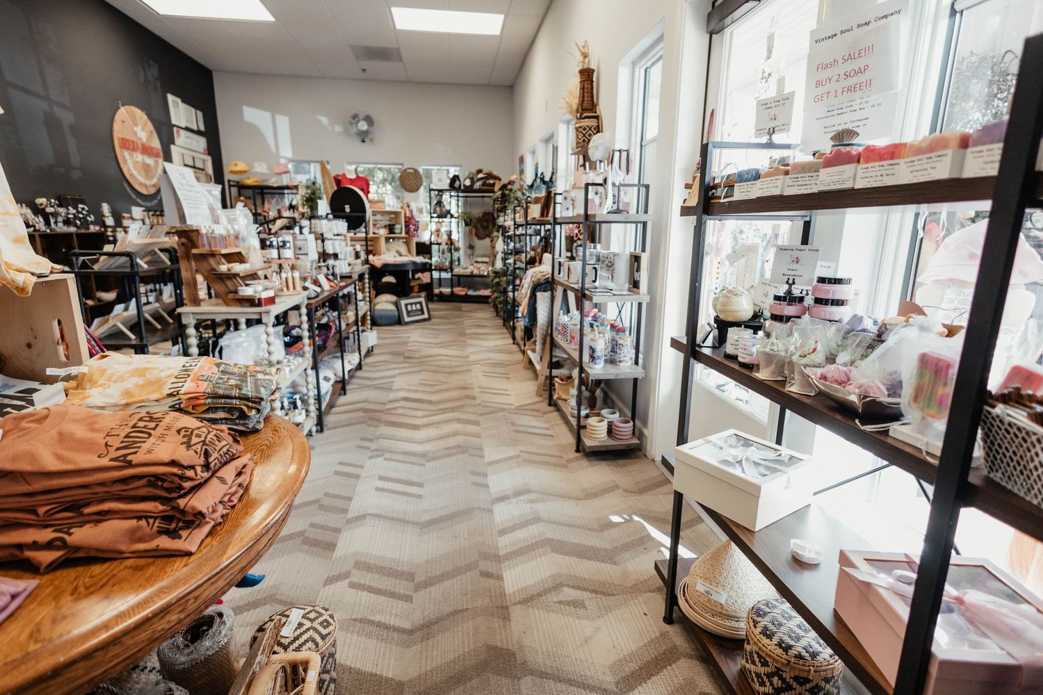 Boutique interior with herringbone pattern flooring and industrial shelving displaying various retail items.