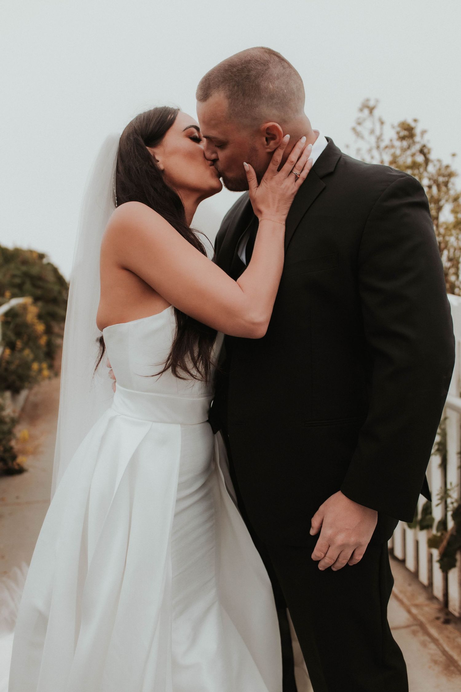 An intimate wedding portrait of a couple sharing a passionate kiss outdoors.