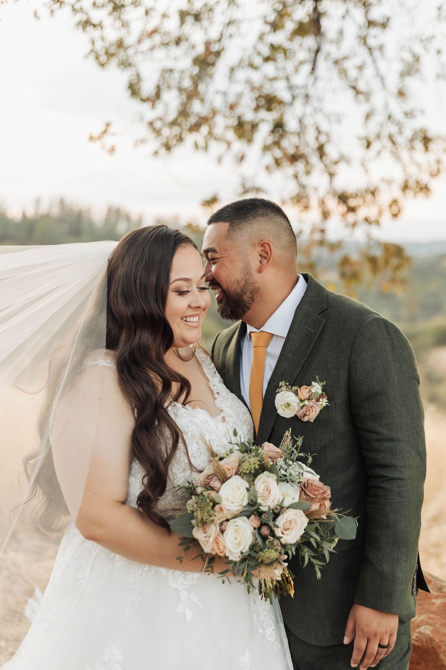 Intimate outdoor wedding portrait with couple embracing against scenic autumn backdrop.