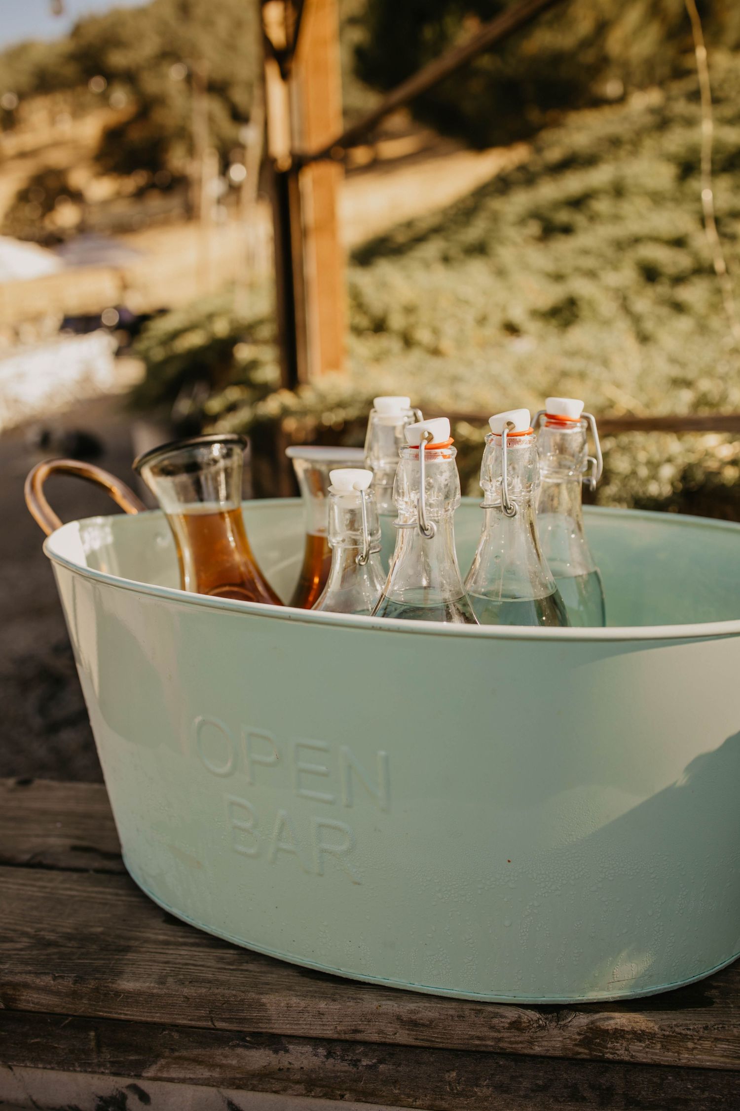 Mint green vintage-style drink tub filled with glass bottles on wooden surface.