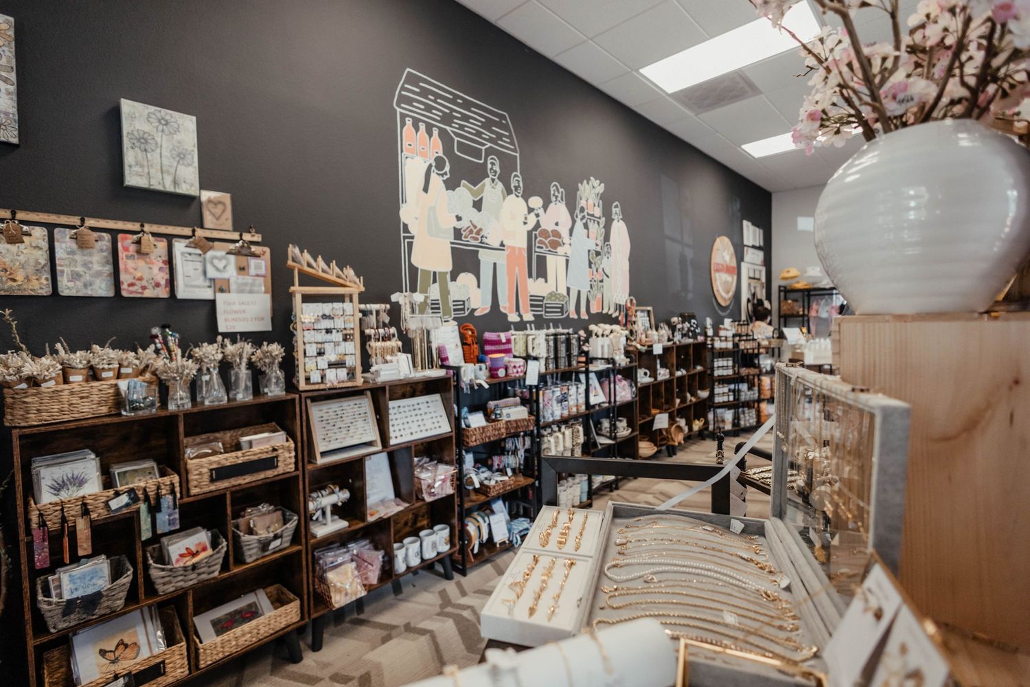Modern retail space with dark accent wall featuring shelved products and hanging paper lantern decorations.