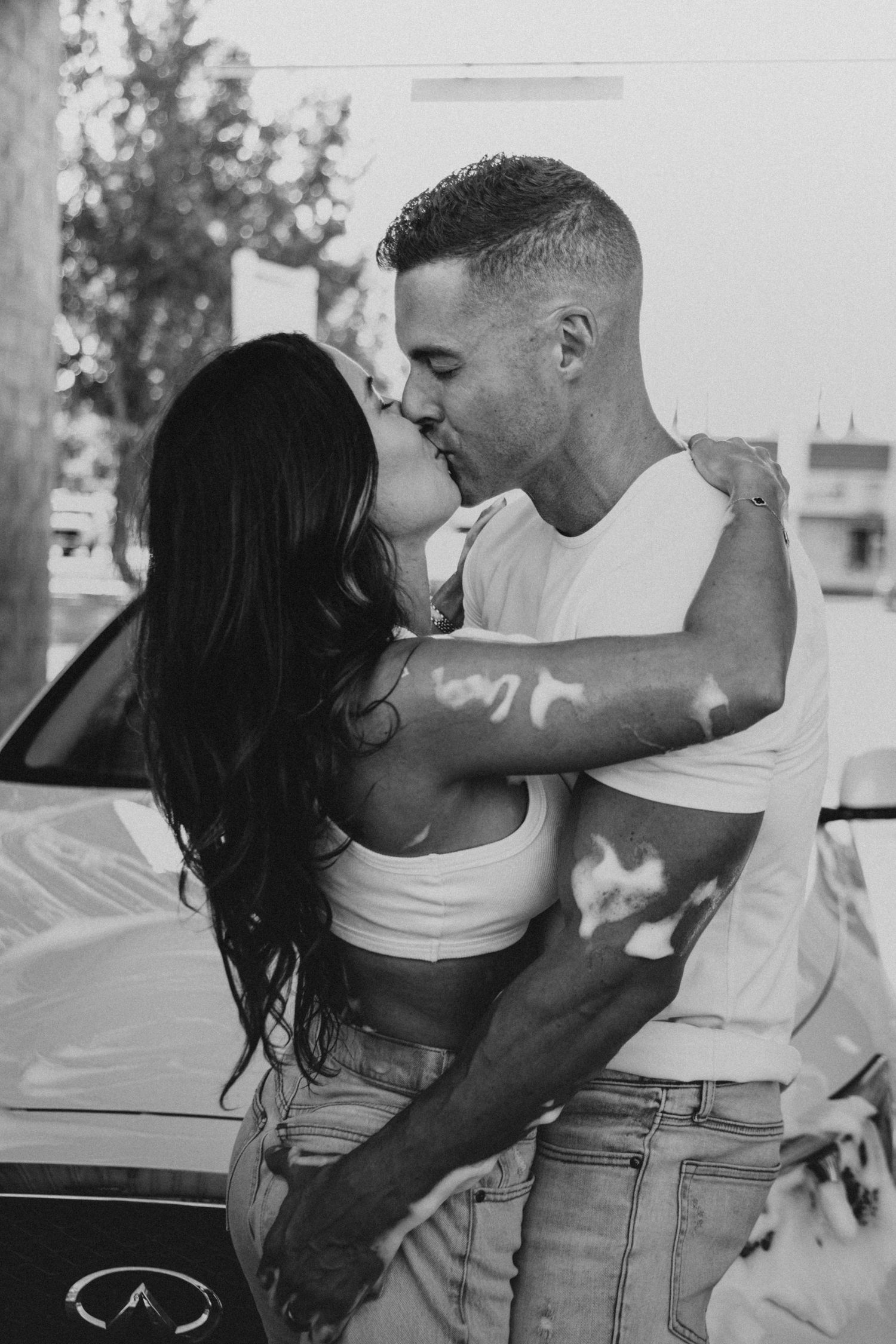 Couple in casual attire sharing intimate moments in black and white.