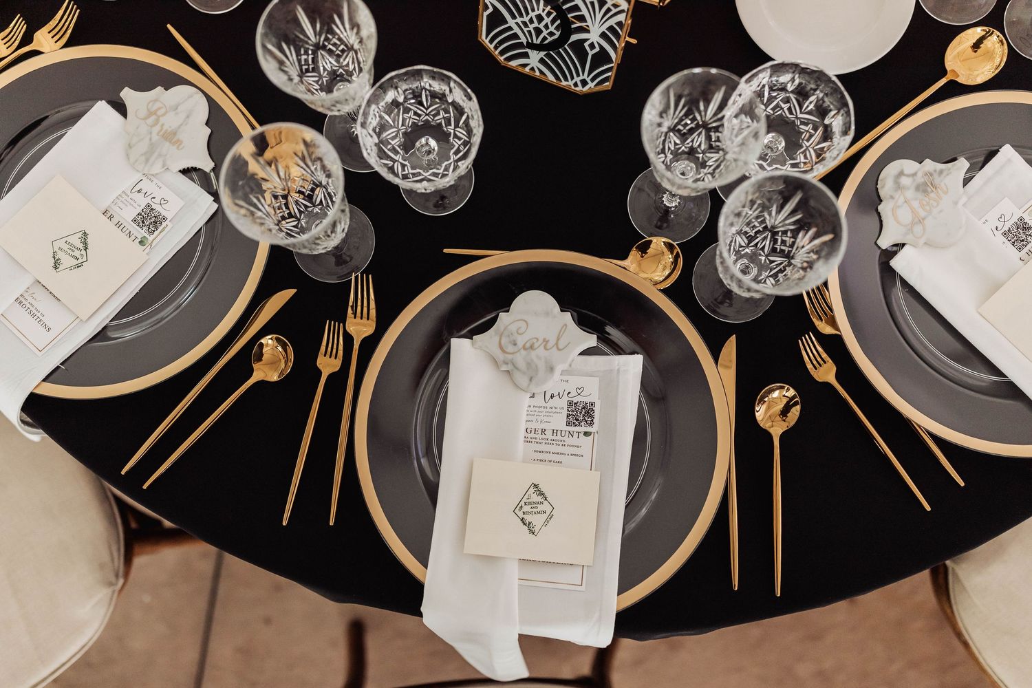 Elegant place settings with crystal glassware and gold accents on a dark tablecloth.