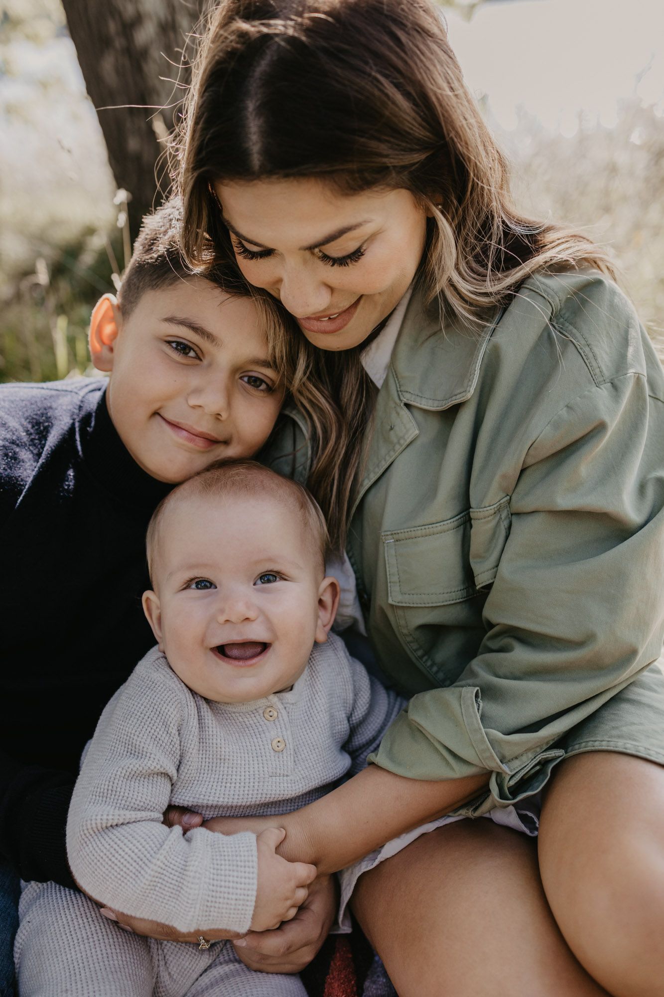 Intimate family moment captured outdoors with joyful baby and loving embraces.