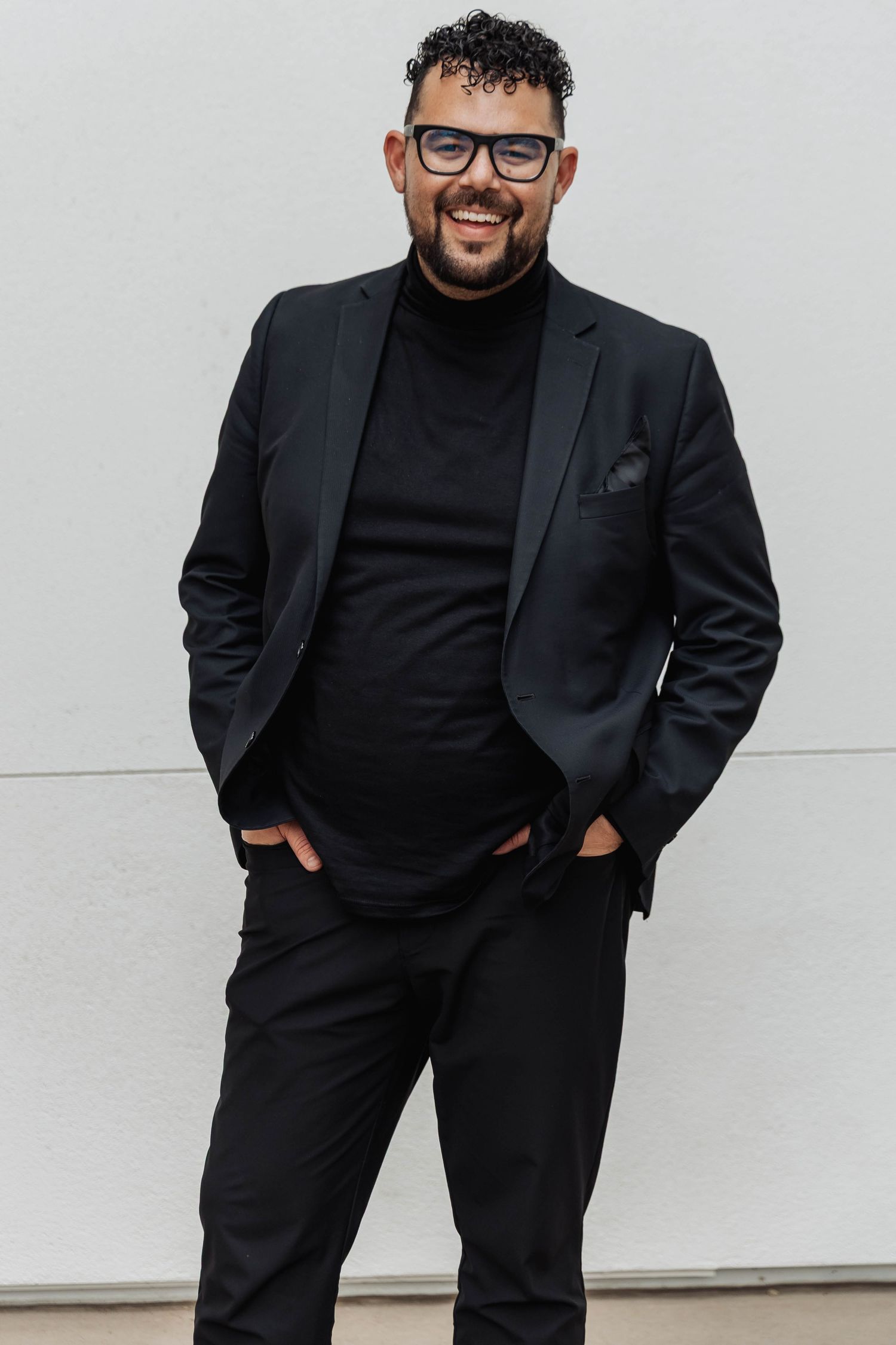 Professional portrait series showing someone in a black turtleneck and blazer posing against a white background.