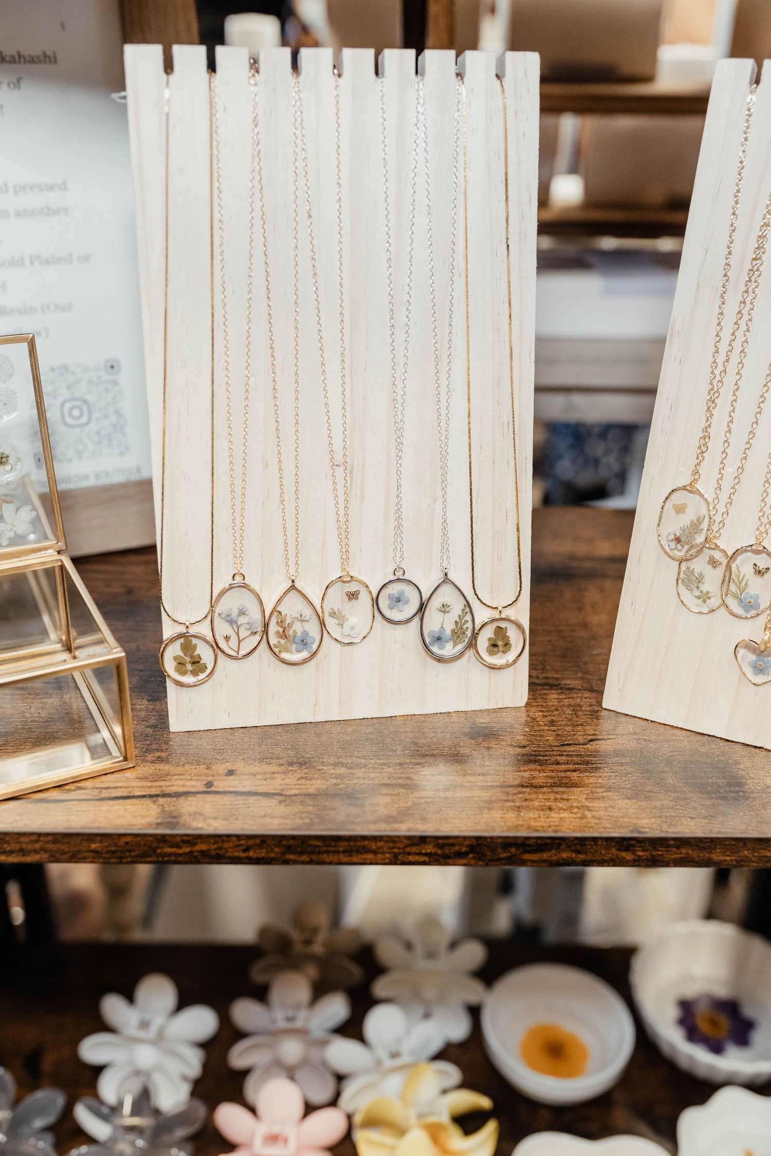 Display of dainty gold necklaces arranged on white wooden stands.
