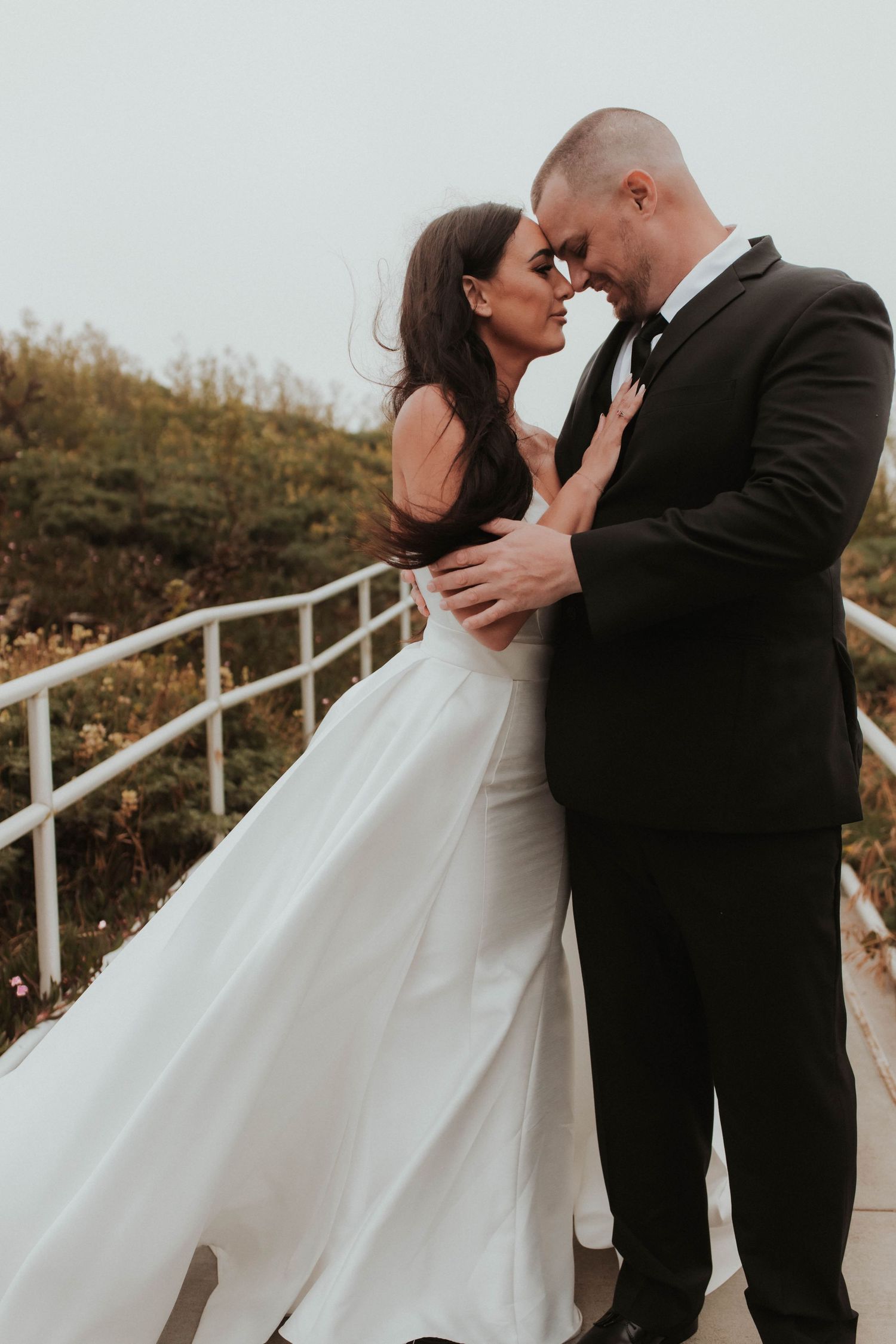 A romantic wedding moment captured on stairs with couple in formal attire sharing an intimate embrace.