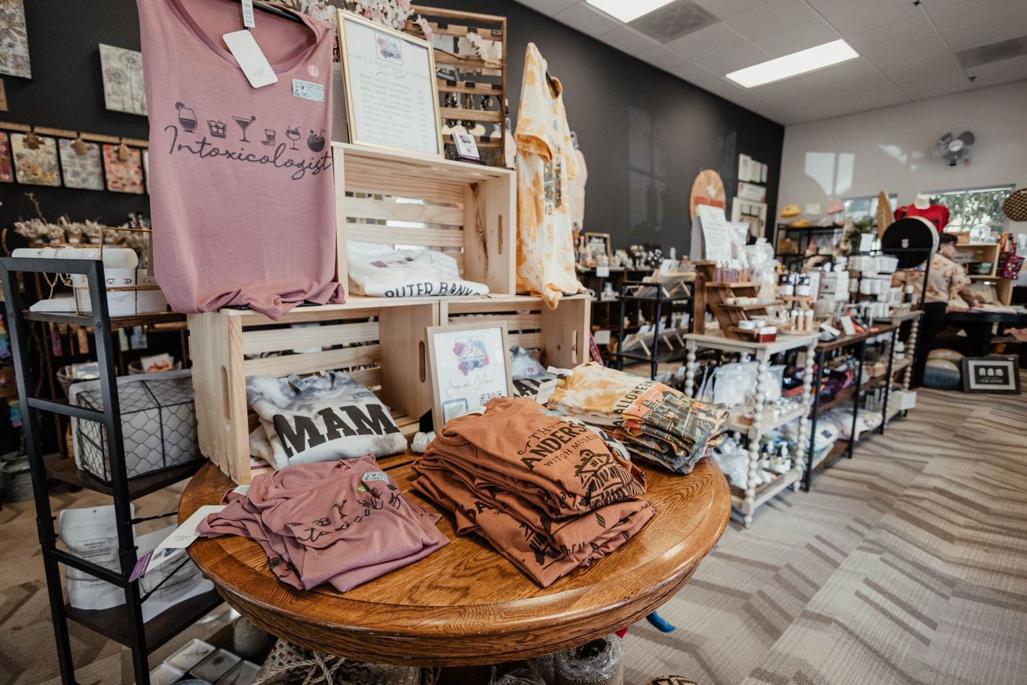 Retail store interior with clothing displays and t-shirts arranged on wooden table.