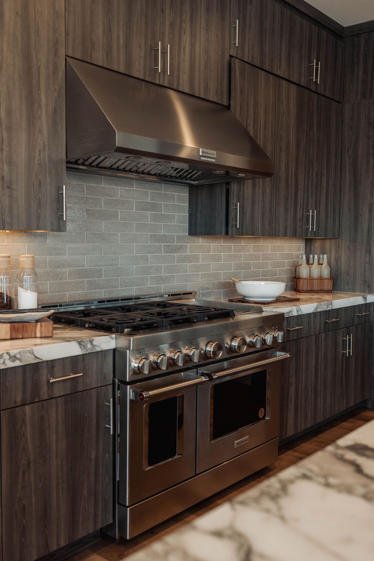 Professional kitchen featuring multiple ovens and cooktops with dark wood cabinetry.