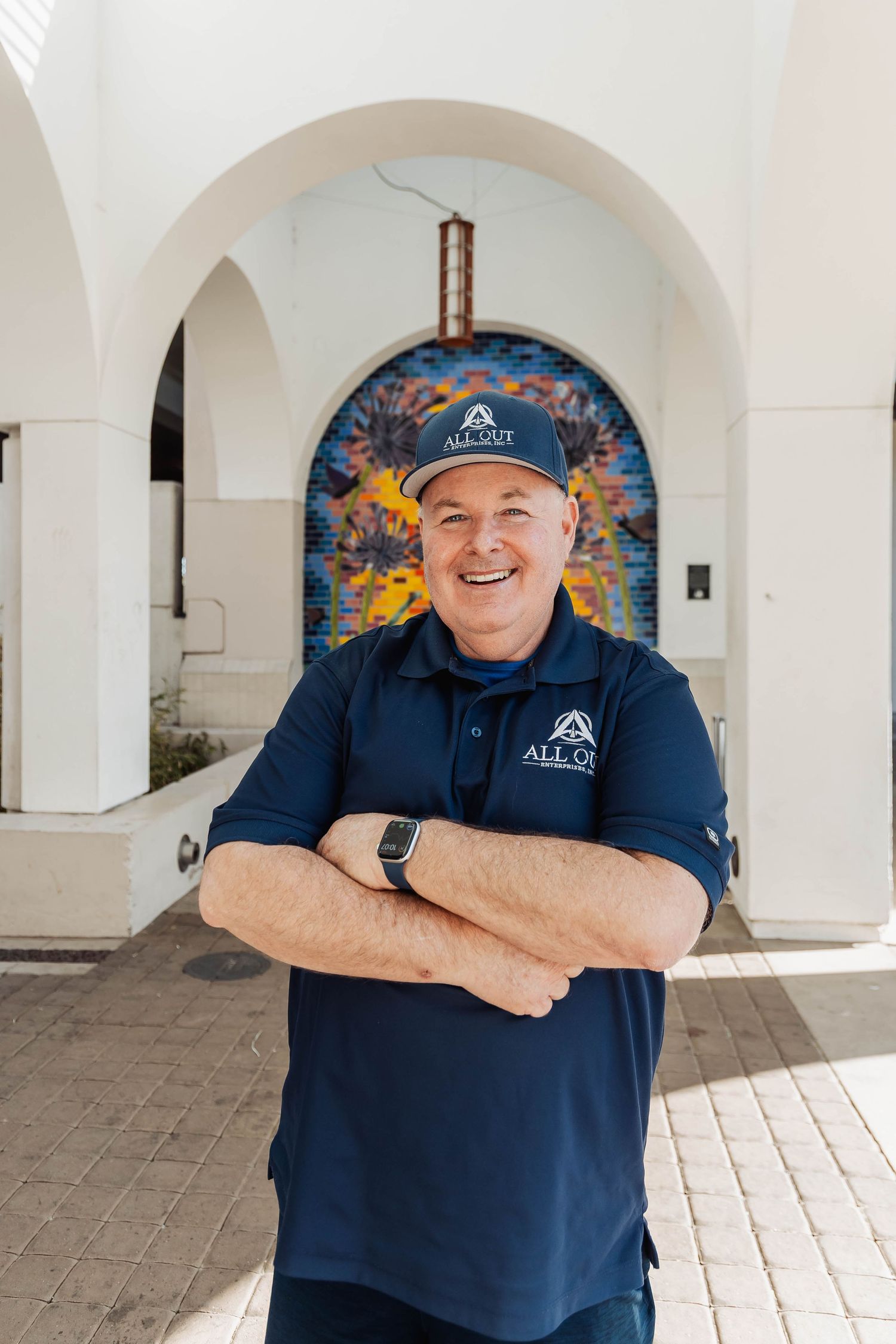 Person in navy uniform smiling under white arched walkway.