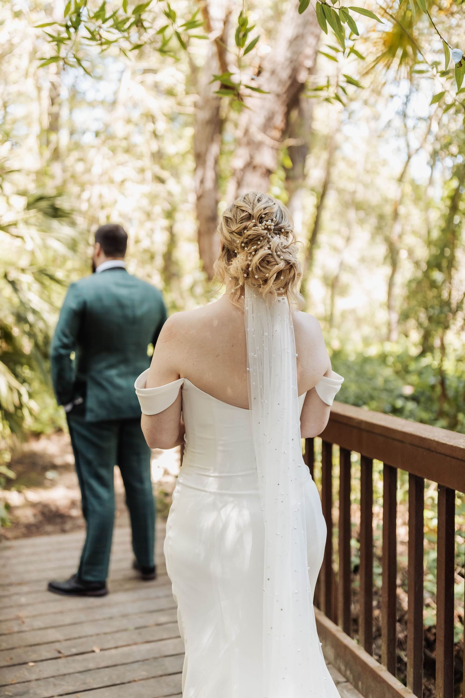 Wedding couple shares a private moment on a wooden deck surrounded by trees.