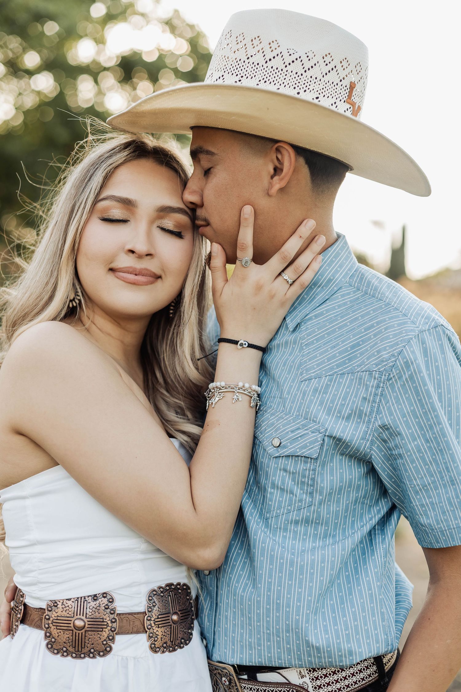 Intimate couple's portrait session at sunset with cowboy hat and western fashion elements.