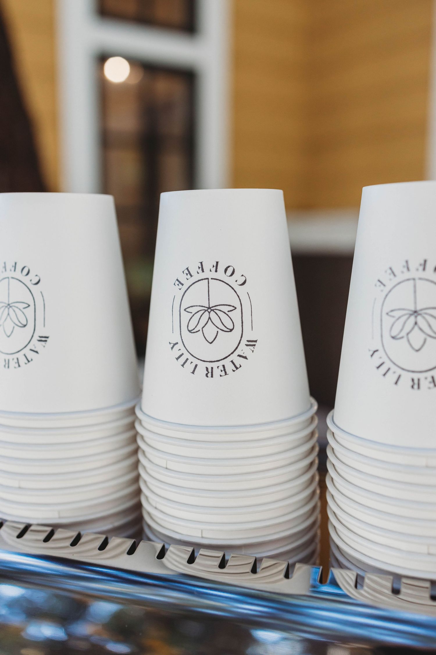 Stacked white paper coffee cups with minimalist logo branding.