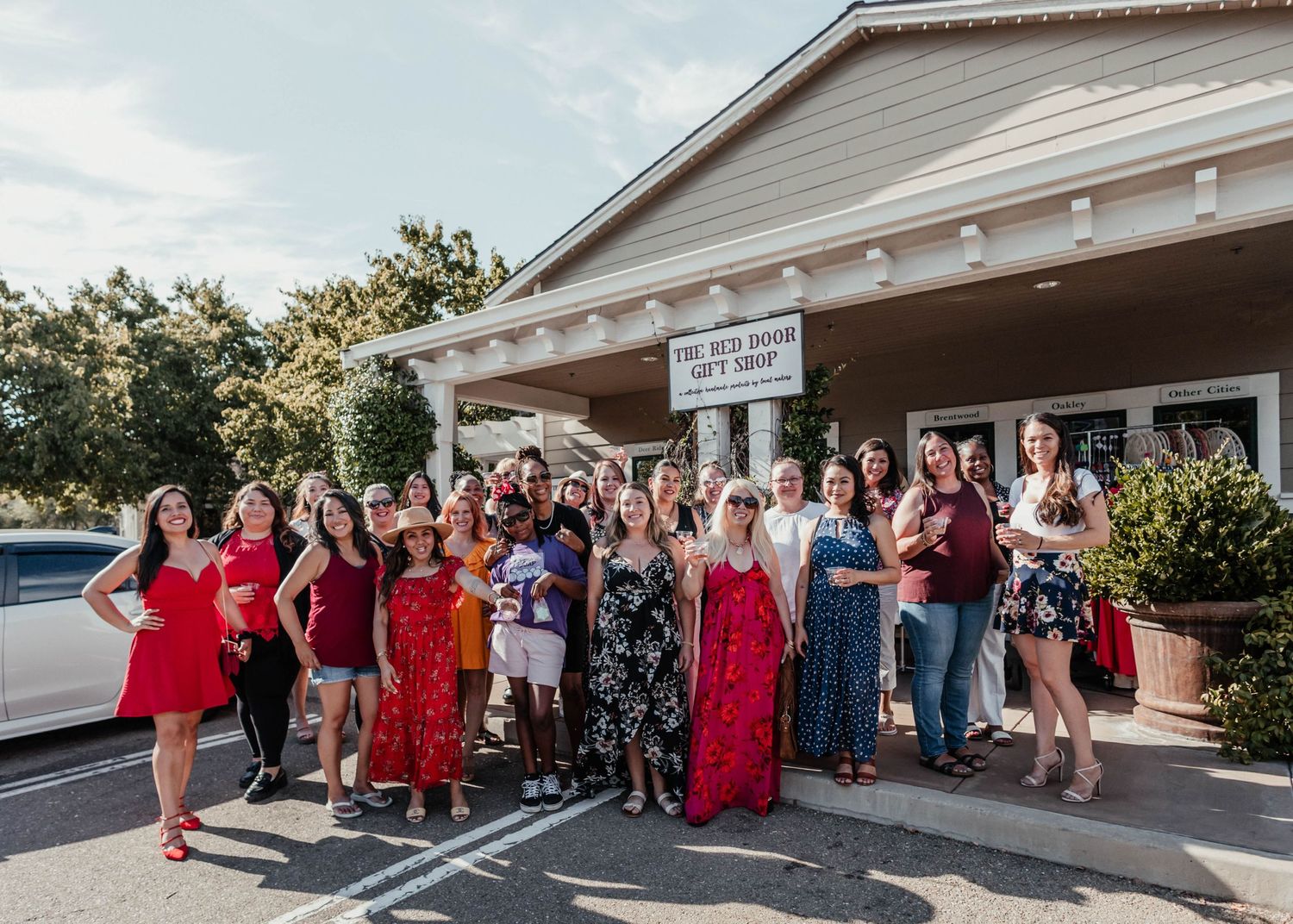 A group photo taken outside a building with people wearing colorful dresses and casual clothes.